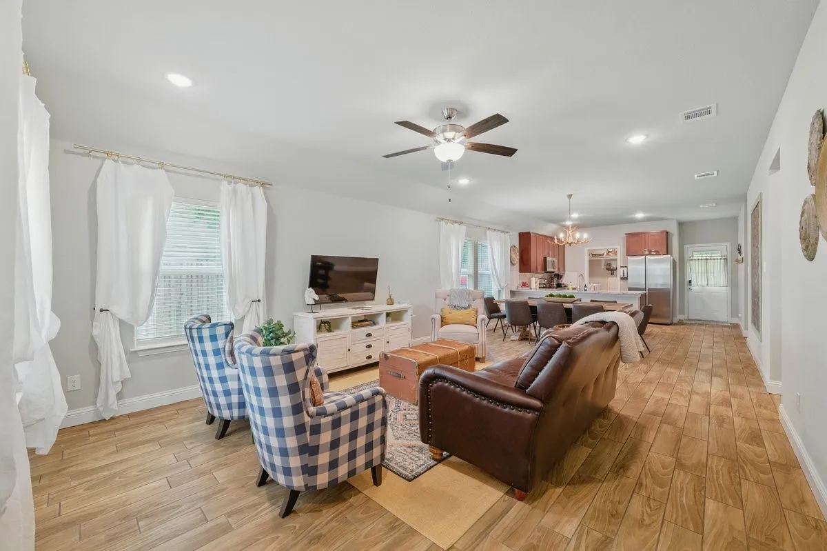 Open-concept living area featuring wood-finish flooring throughout, recessed lighting, and a ceiling fan with integrated light fixture