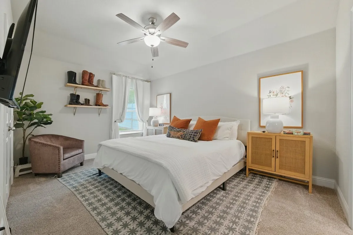 Recessed window with sheer white curtains, wall-mounted display shelving, and ceiling fan with lighting