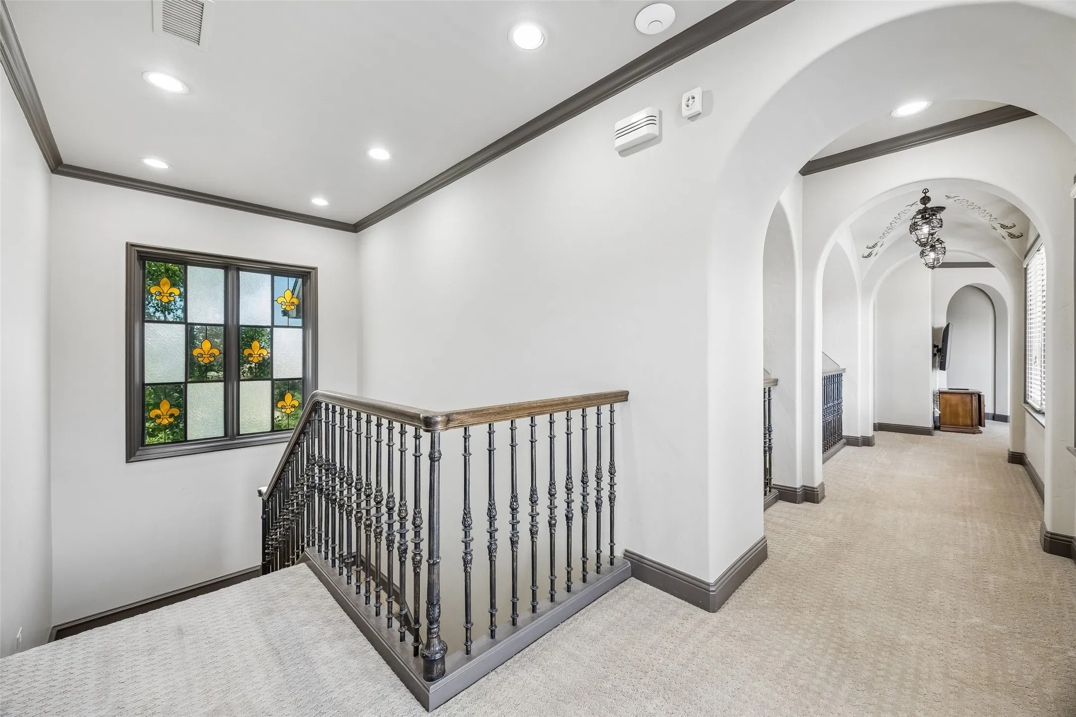 Second stairwell near media room features custom stained glass. Wide hallways on second floor help bring in more natural light to the home!