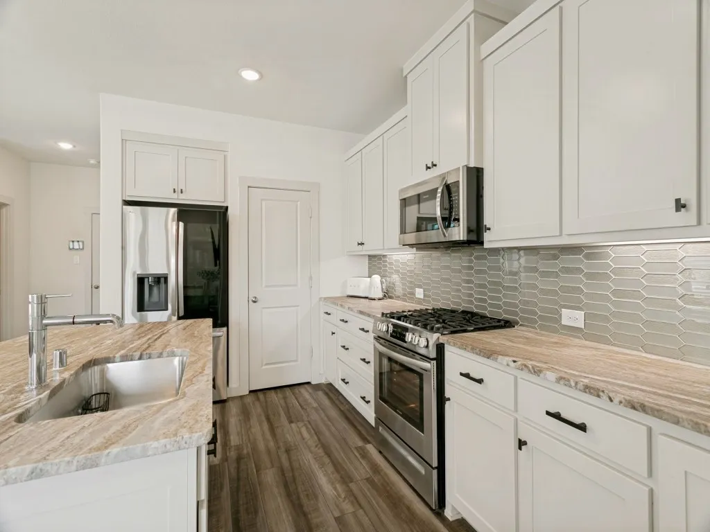 Kitchen featuring designer backsplash  backsplash, and natural stone countertops