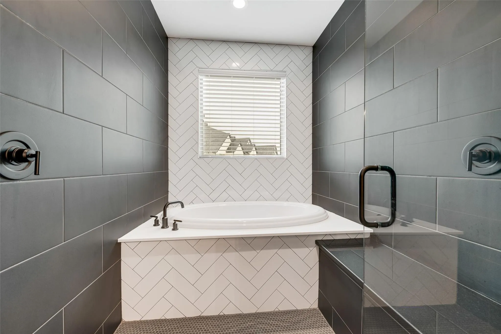 Contemporary bathroom featuring a built-in soaking tub with deck-mounted fixtures, integrated shower bench, and a glass-enclosed shower with matte black hardware