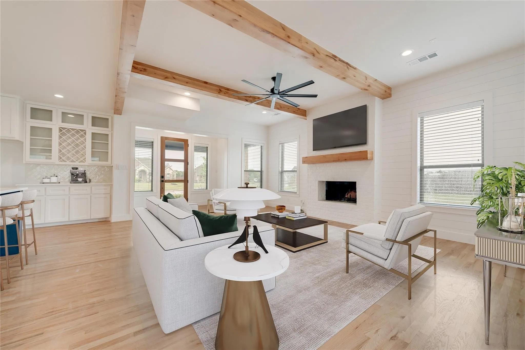 Open-concept living area with wood-finish flooring, exposed wood beams, and shiplap accent walls