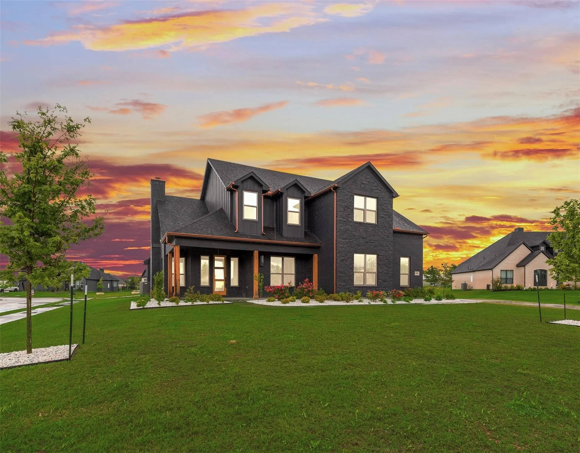 Modern farmhouse exterior featuring dark siding and brick accents