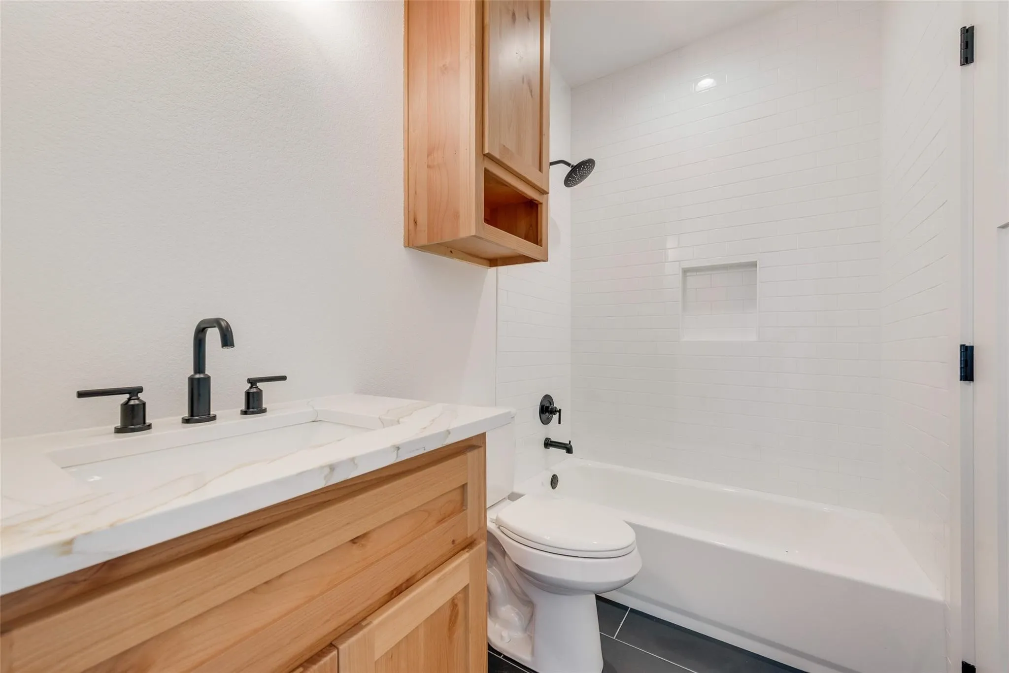 Bathroom featuring a light wood-finish vanity with an integrated sink and matte black fixtures