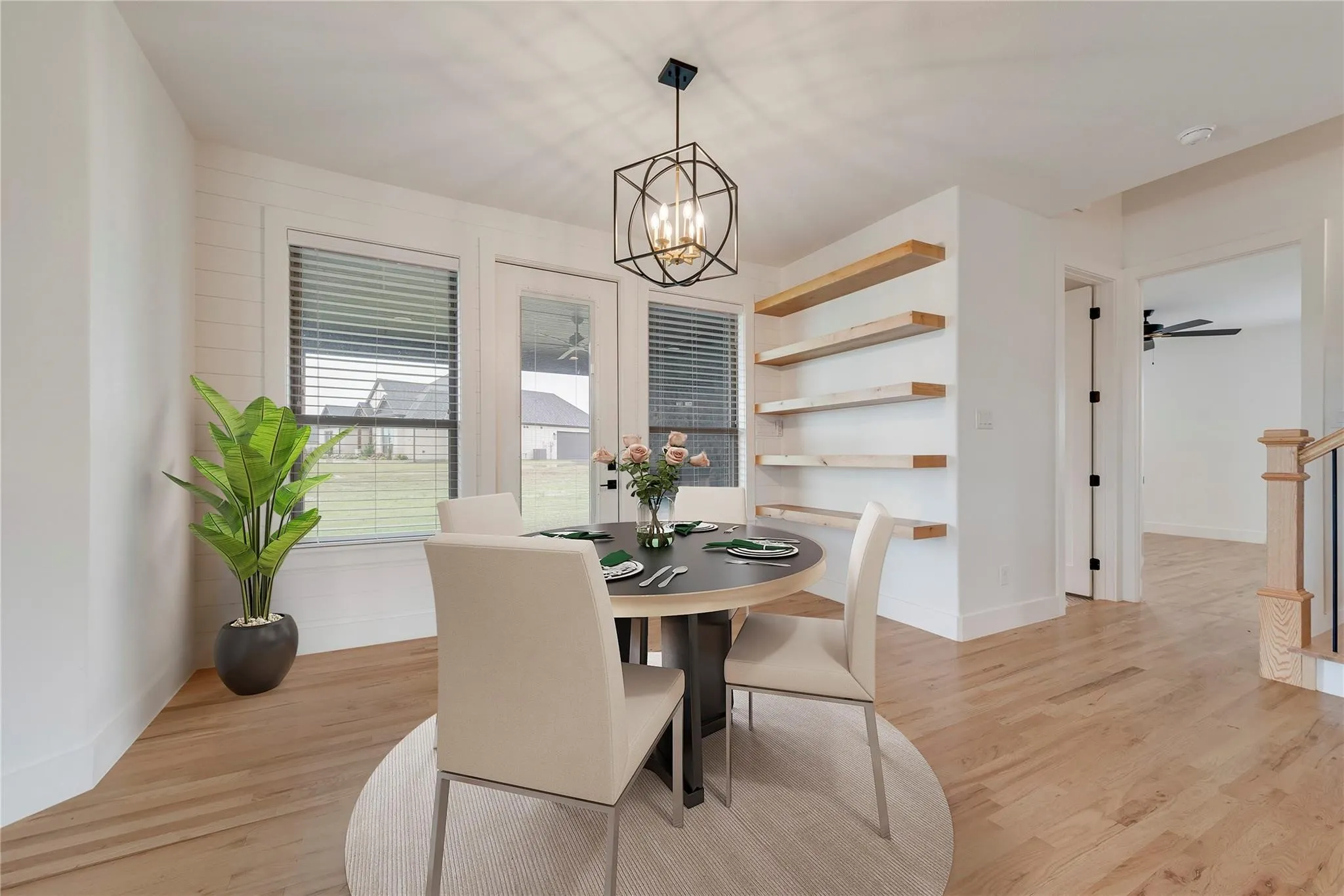 Dining area featuring wood-finish flooring, a geometric pendant light fixture, and built-in floating wood shelves