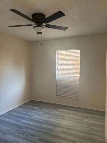 Wood-finish flooring, ceiling fan with integrated lighting, and window with blinds