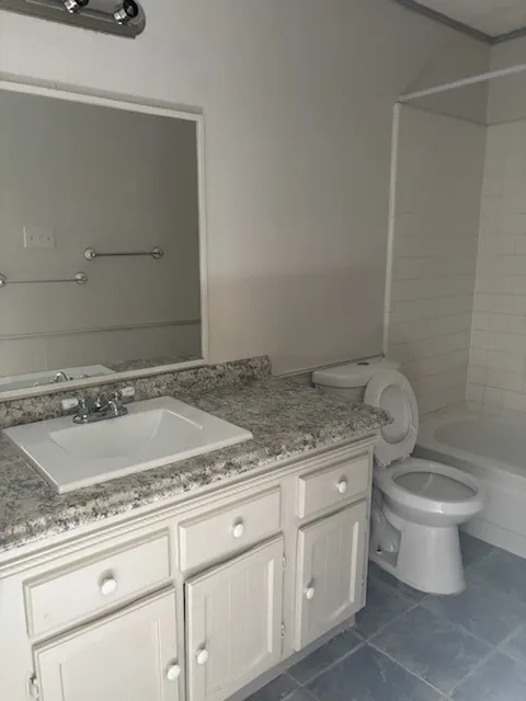Vanity with an integrated sink, speckled countertop, and white cabinetry
