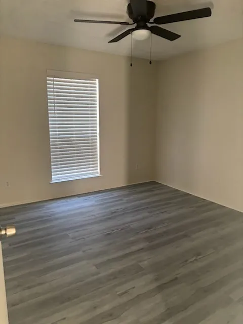 Room featuring wood-finish flooring, a window with horizontal blinds, and a ceiling fan with integrated lighting