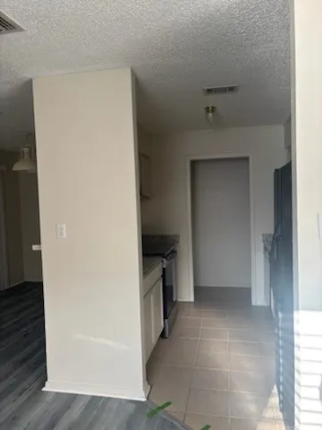 Wood-finish flooring transitions to square tile flooring, complemented by white cabinetry and stainless steel appliances