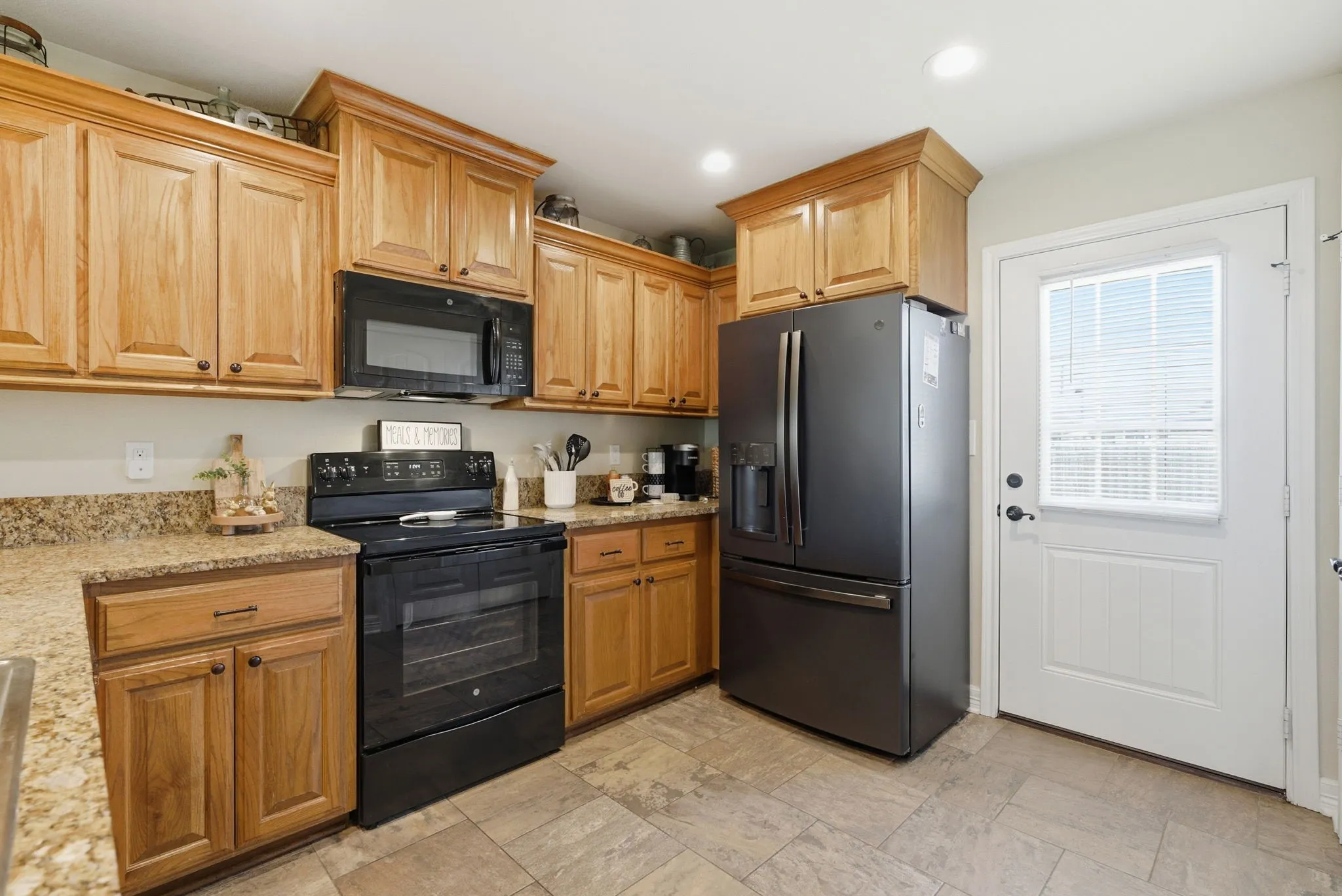 Kitchen featuring wood cabinetry, light-toned countertops, tile flooring, and integrated appliances