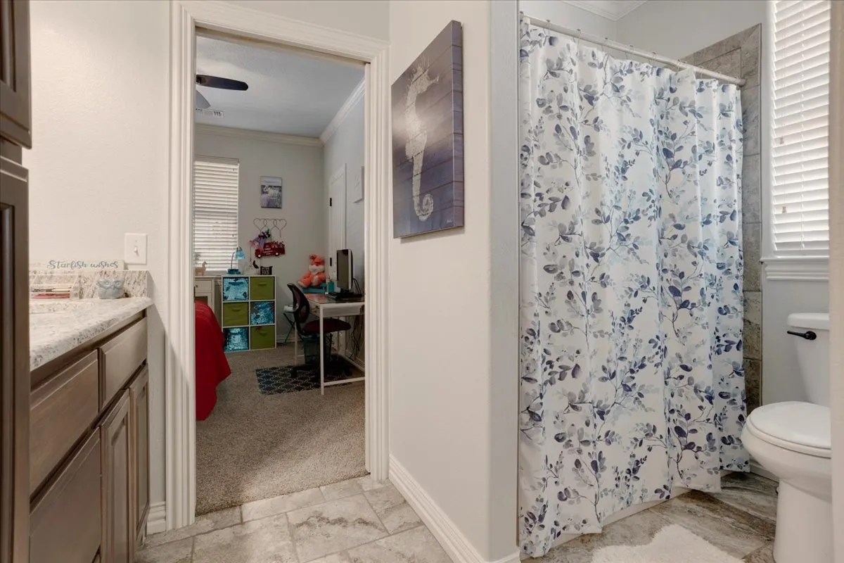 Bathroom featuring a shower with tiled surround, a toilet, and a vanity with a light-colored​​‌​​​​‌​​‌‌​‌‌​​​‌‌​‌​‌​‌​​​‌​​ countertop