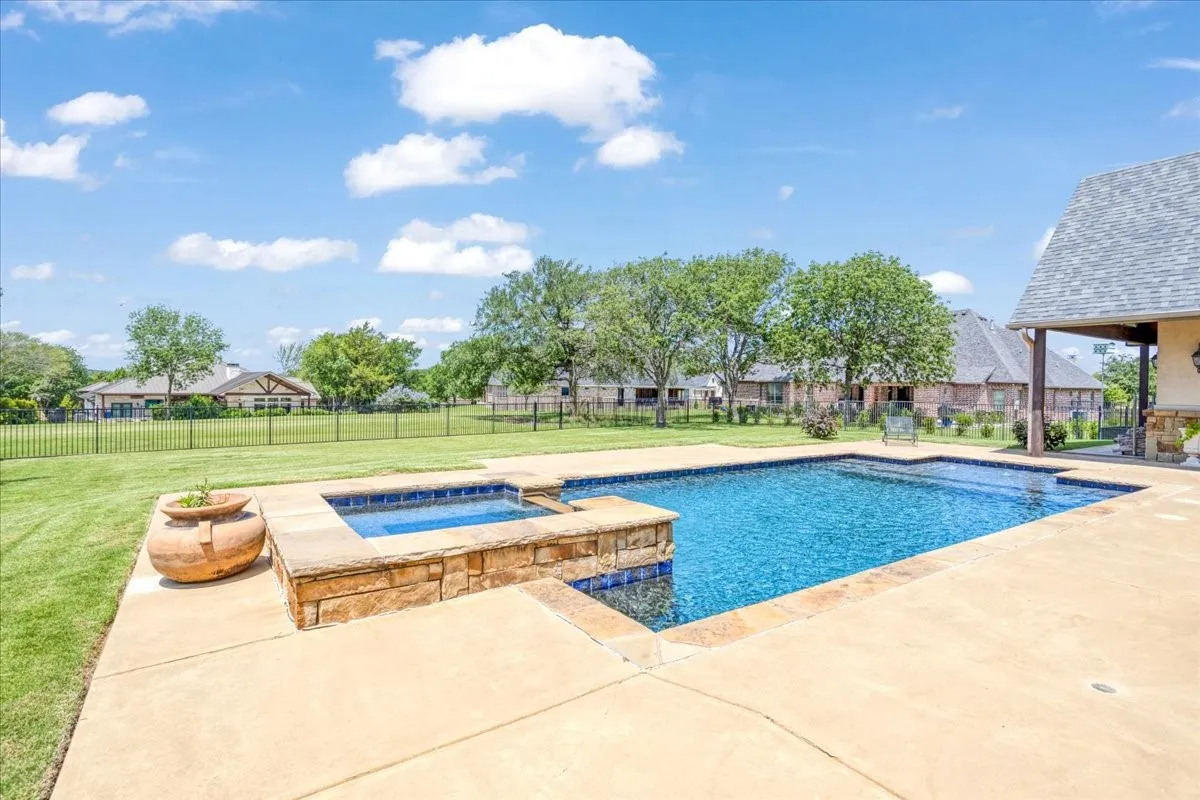 Rectangular swimming pool with a stone-clad spa, surrounded by a concrete patio