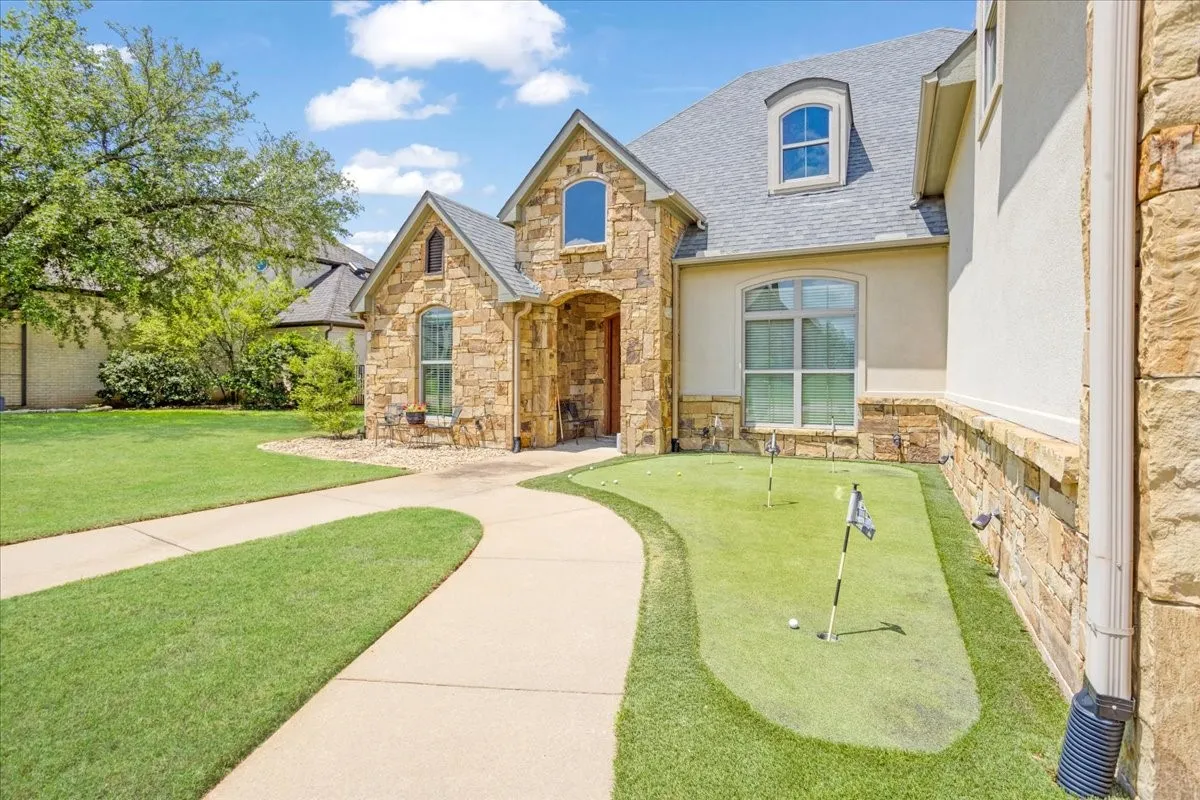 Elegant stone and stucco exterior with arched entryway and multiple gables