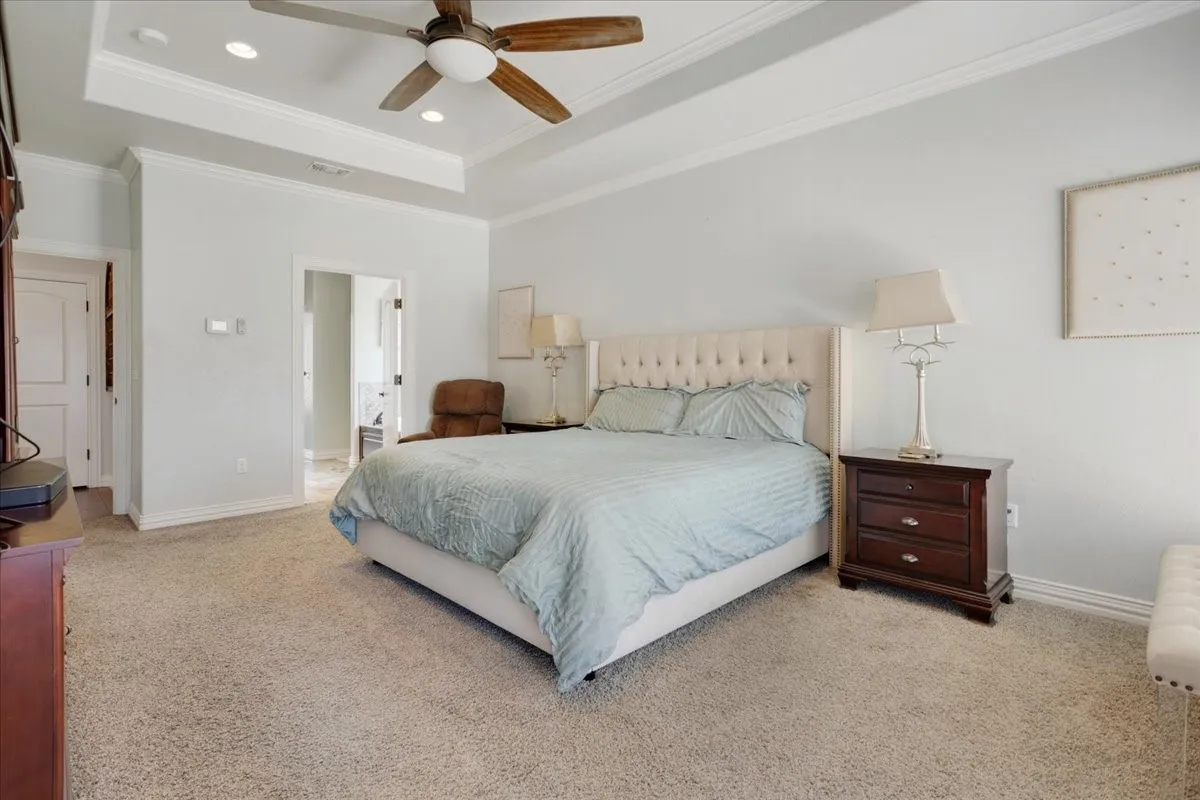 Tray ceiling with recessed lighting and a ceiling fan, light-toned wall paint, and carpeted flooring