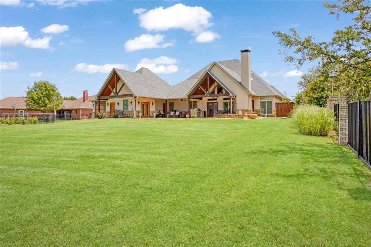 Expansive green lawn with a black metal fence and stone pillars