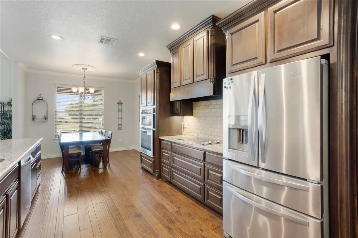 Wood-finish flooring throughout, dark wood cabinetry, stainless steel appliances, and recessed lighting
