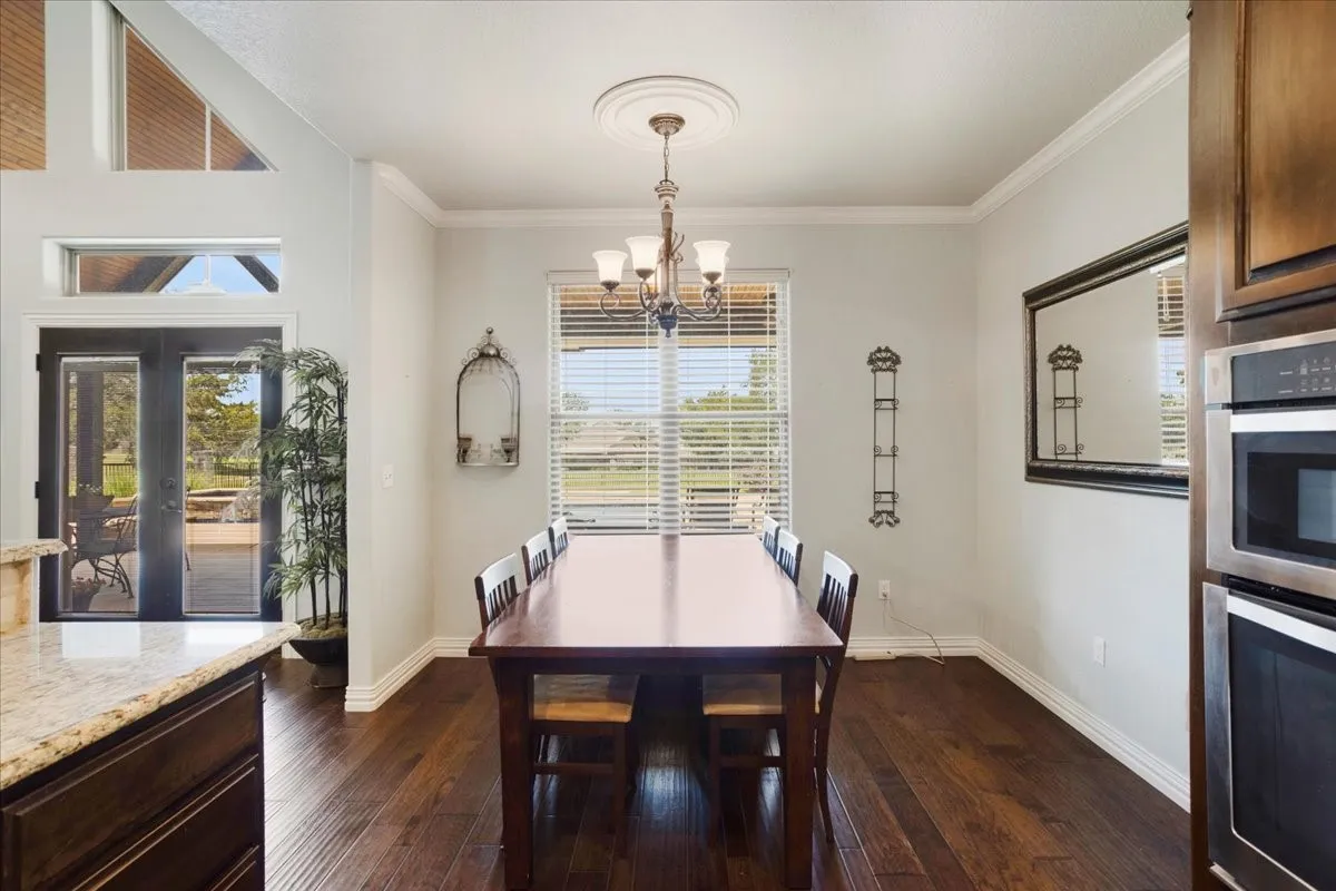 Spacious dining area with wood-finish flooring, crown molding, and a chandelier with ceiling medallion