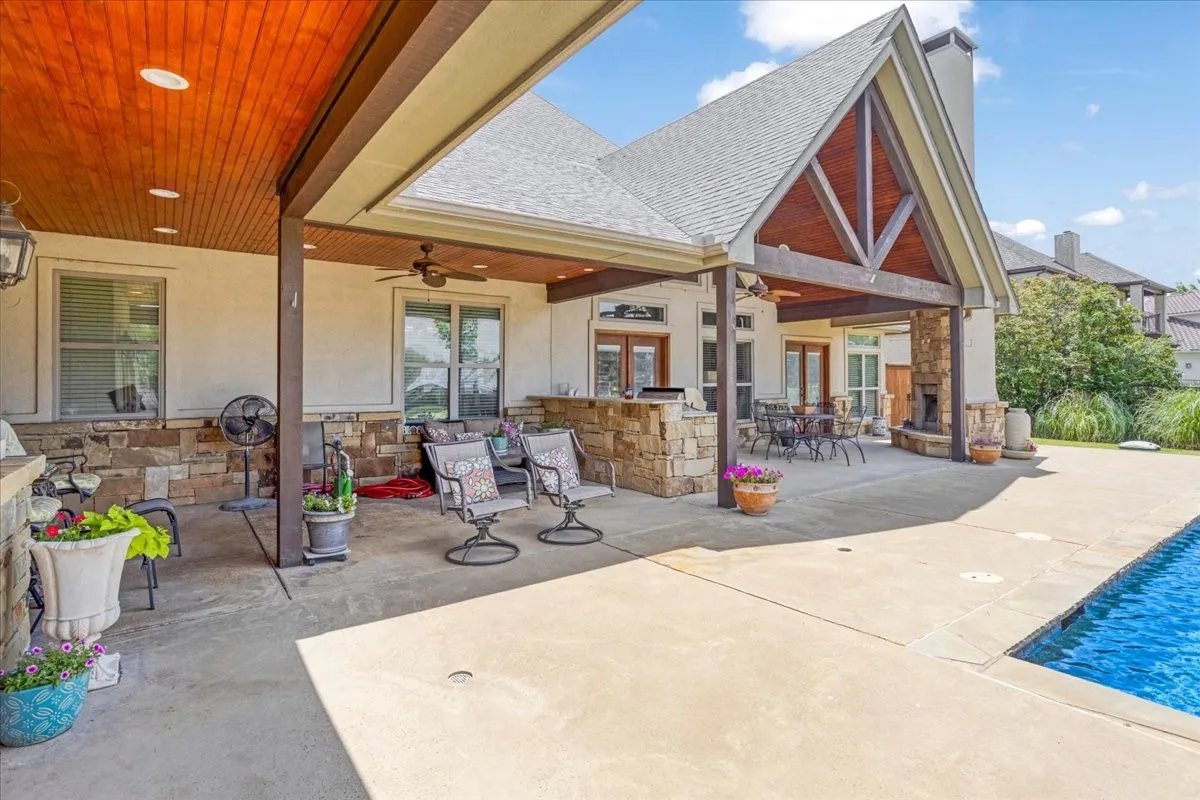 Expansive covered patio with a wood-finish ceiling, stone accent walls, and a built-in outdoor kitchen