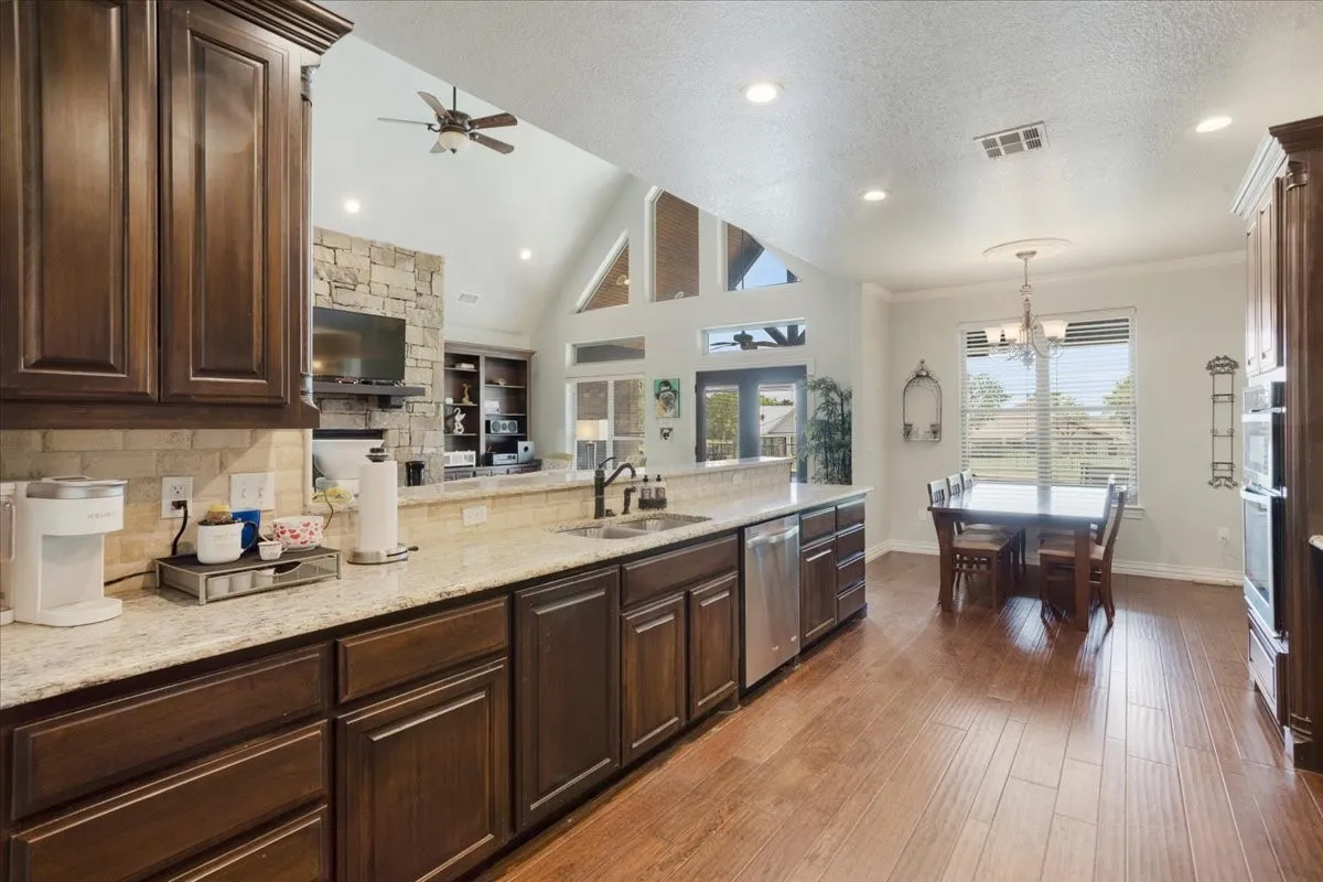 Kitchen and dining area featuring wood-finish flooring, dark wood cabinetry, light-toned countertops, and stainless steel appliances