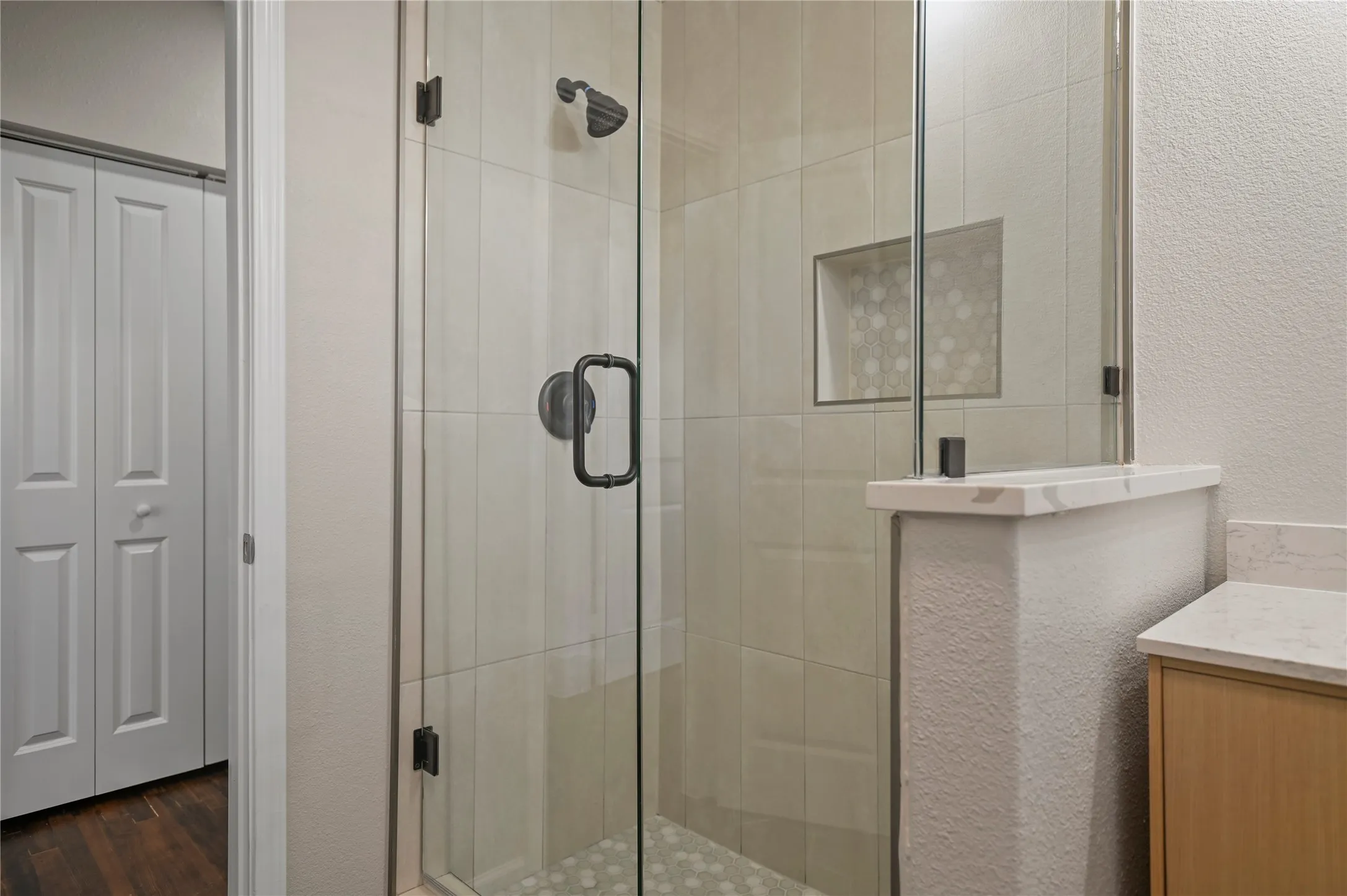 Glass-enclosed shower with matte black fixtures, integrated shower niche, and light-toned wall tiling
