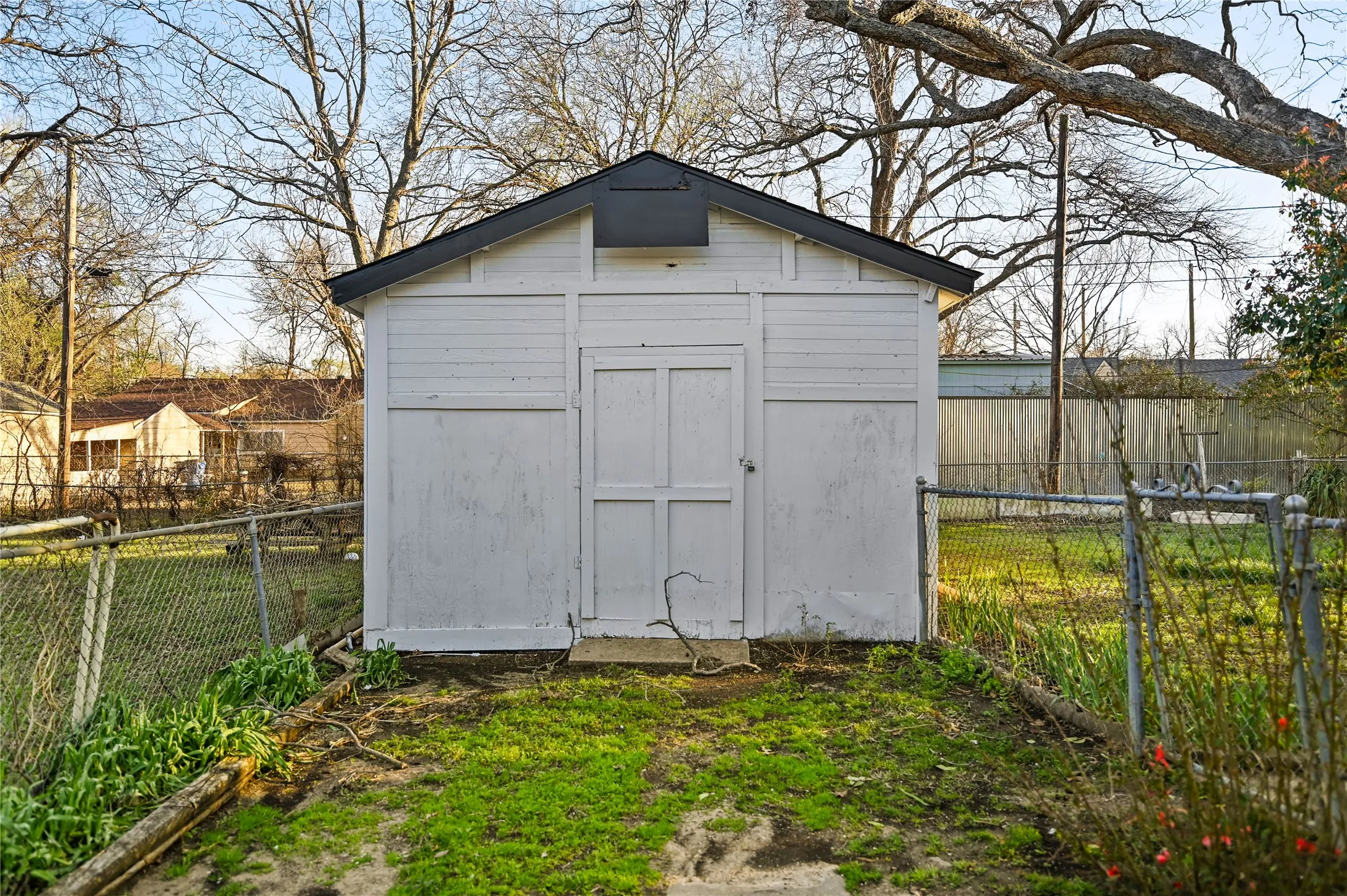 White storage shed with a dark gable roof