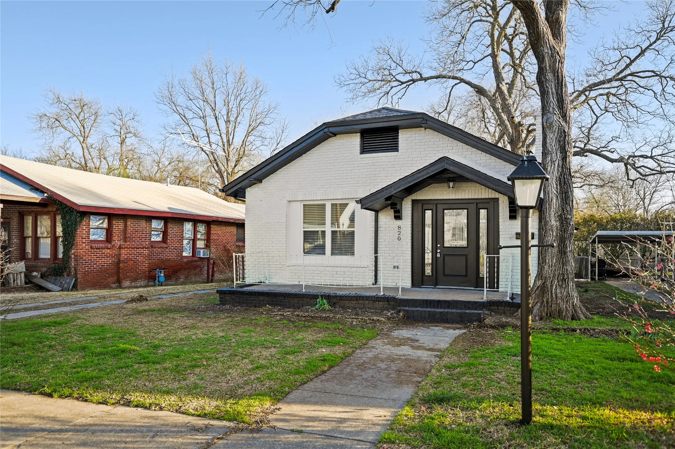 White brick exterior with a black trim roof and a black front door with glass panels
