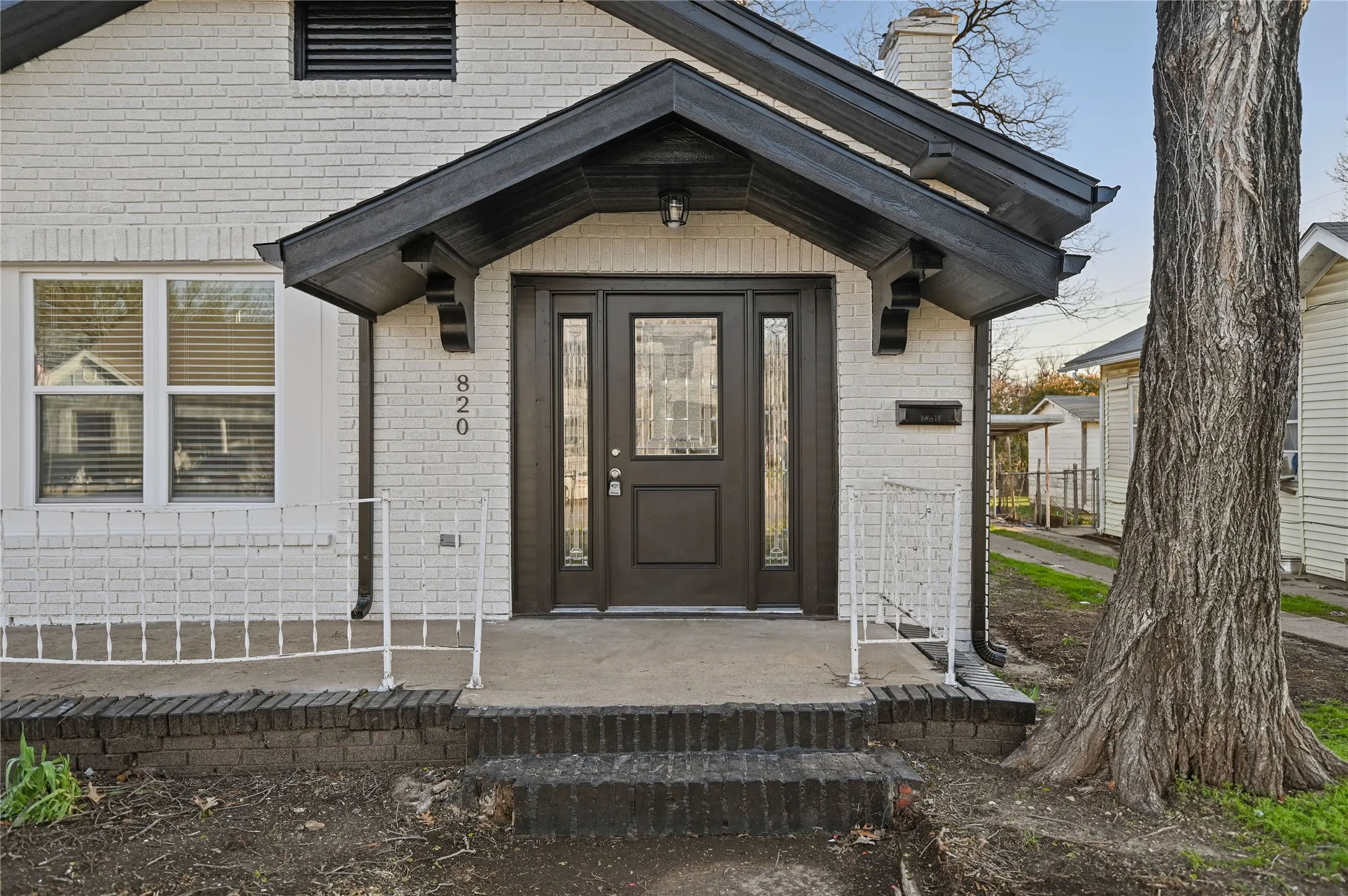 White brick exterior with a dark-stained wood entry door and sidelights