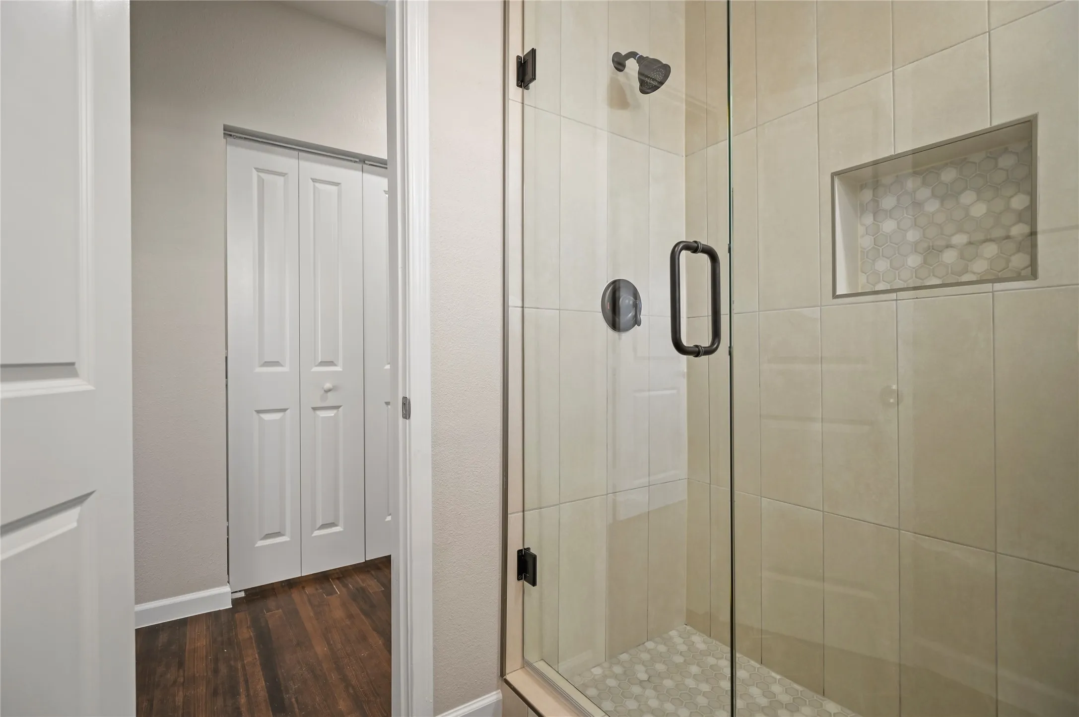 Glass-enclosed shower with a tiled surround and a mosaic tile shower niche