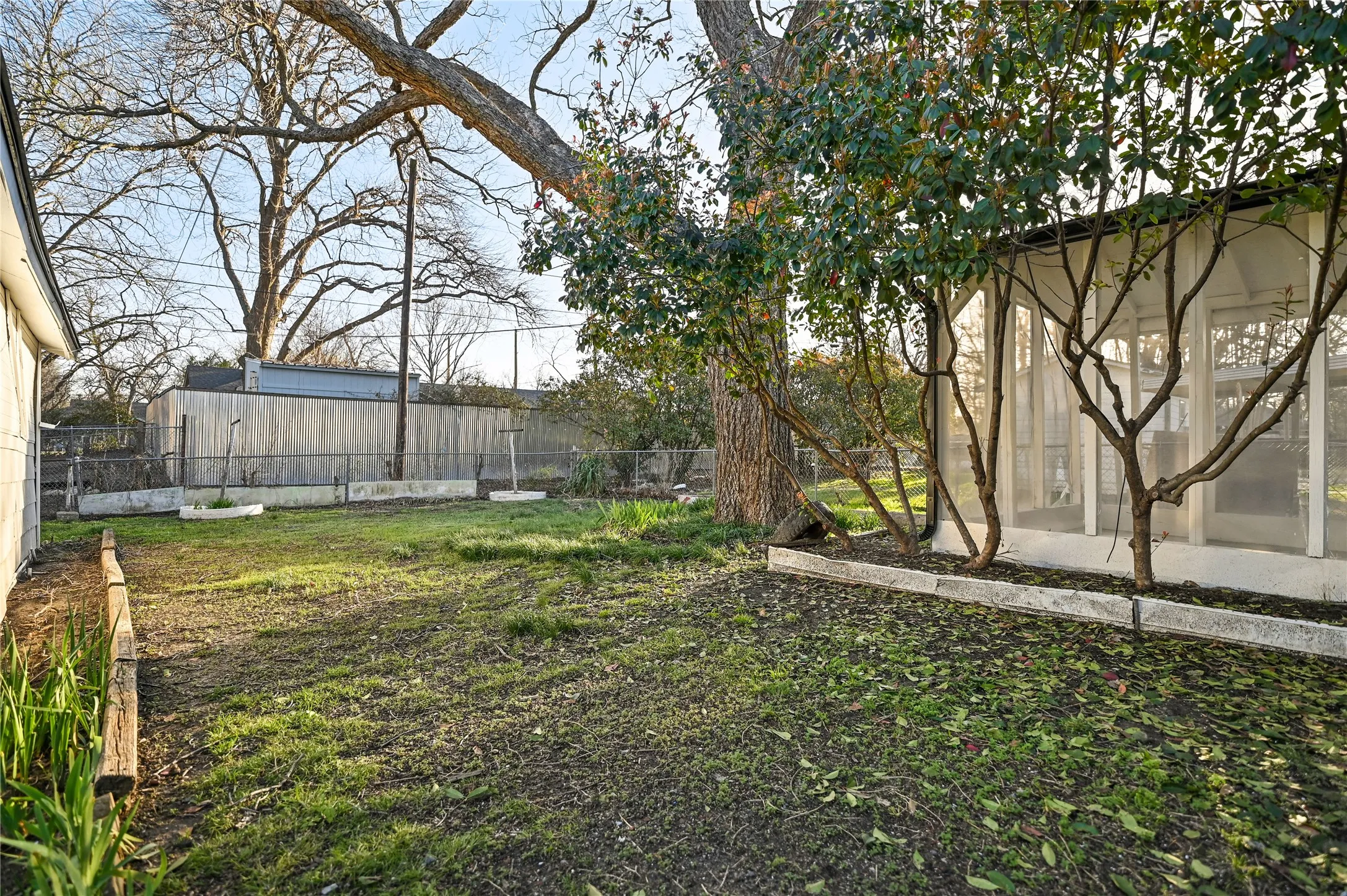 Expansive grassy yard area with mature trees and a screened-in porch structure