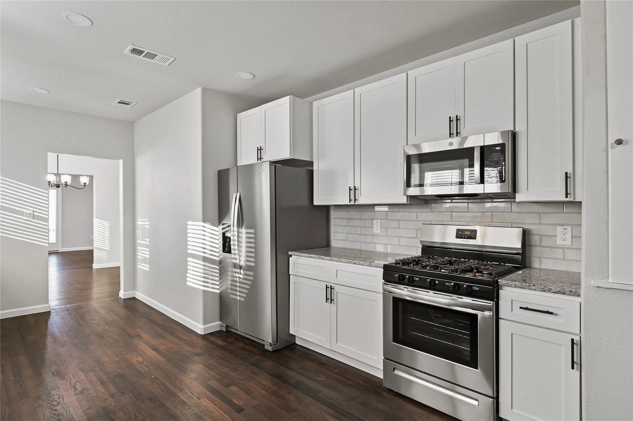 Kitchen featuring stainless steel appliances, white cabinetry, a subway tile backsplash, and stone countertops