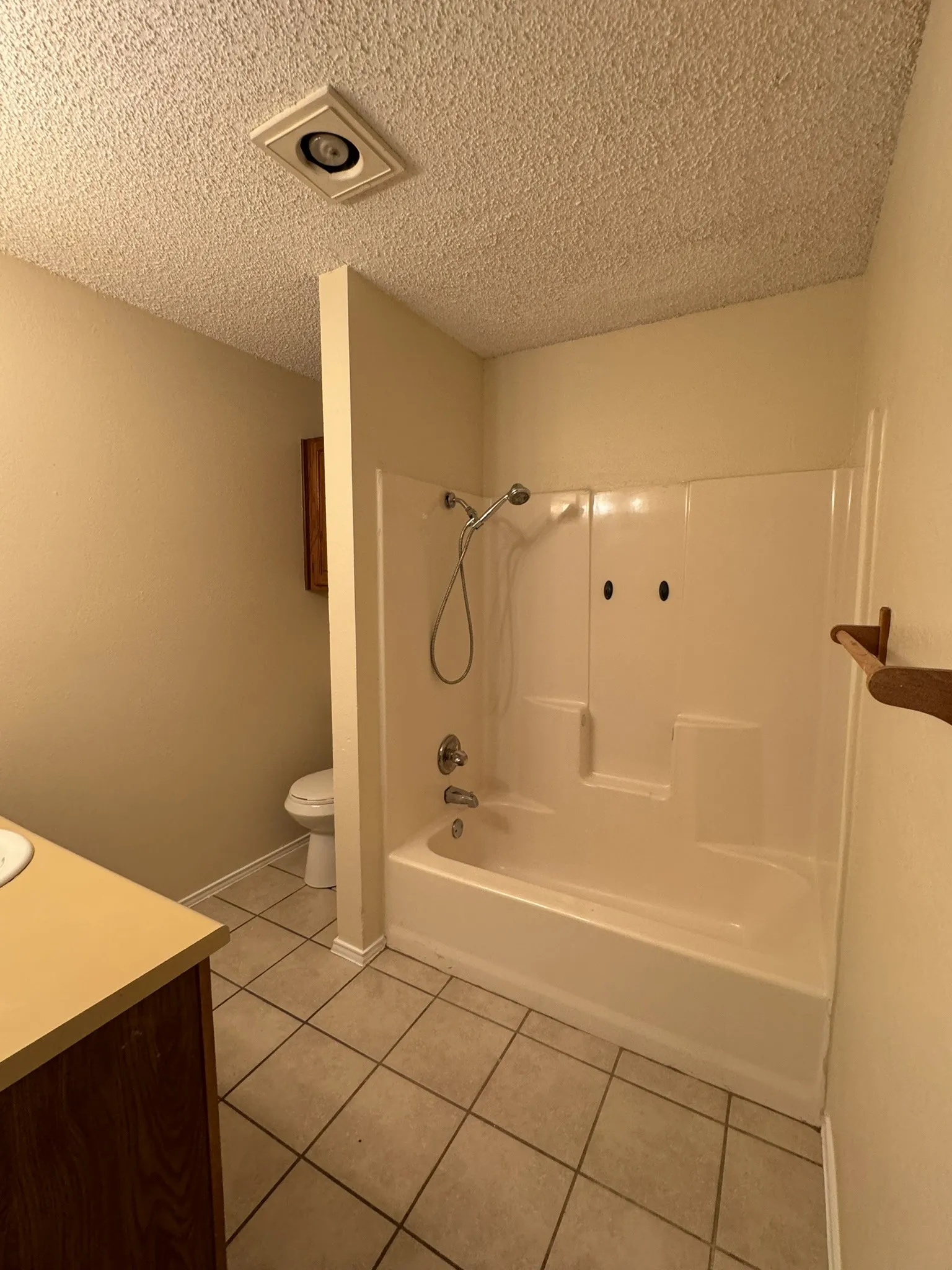Full-size bathtub with integrated shower, chrome fixtures, and tiled flooring