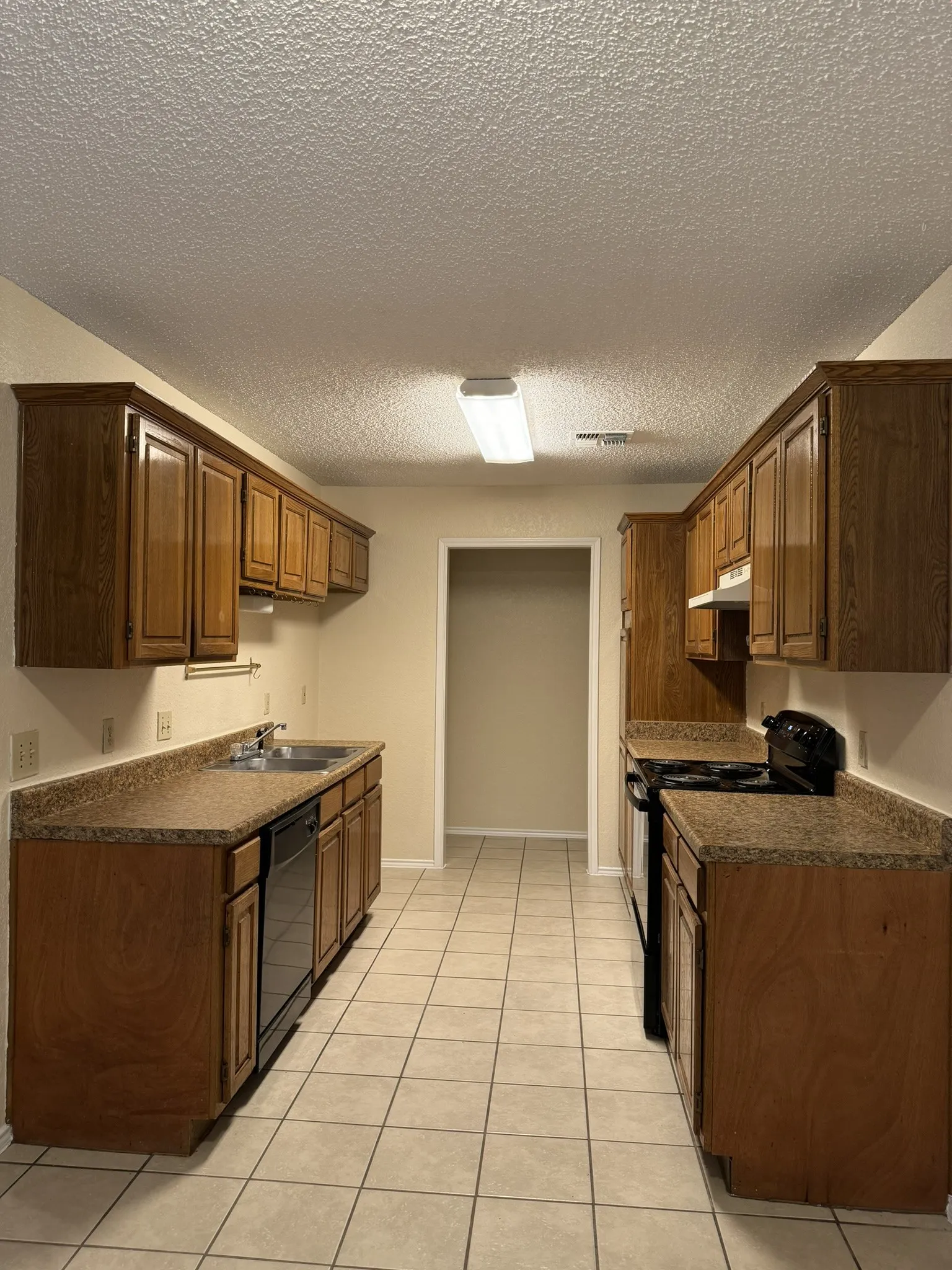 Kitchen featuring wood cabinetry, laminate countertops, tile flooring, and integrated appliances