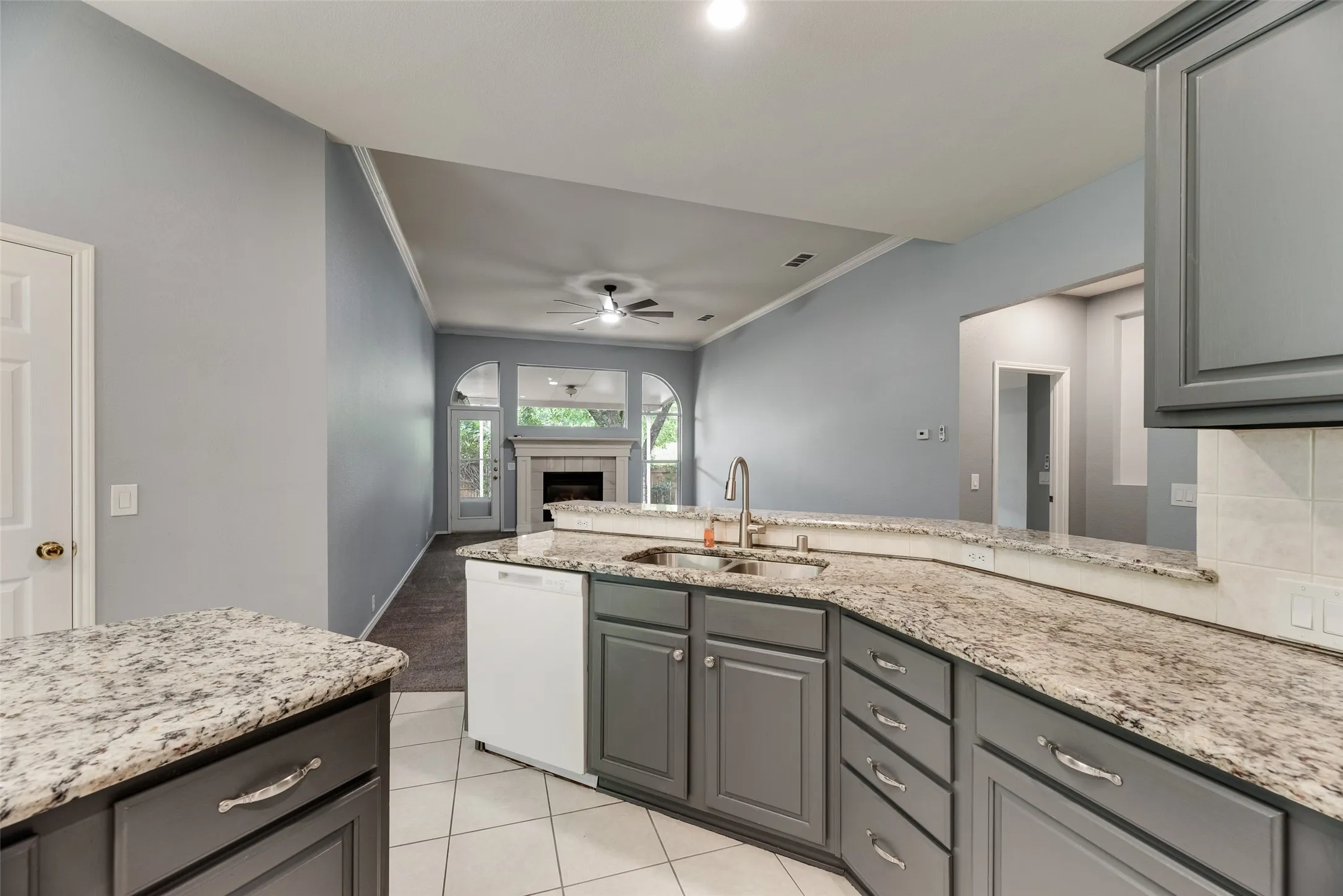 Kitchen with granite countertops, grey cabinetry, stainless steel sink, and tile flooring