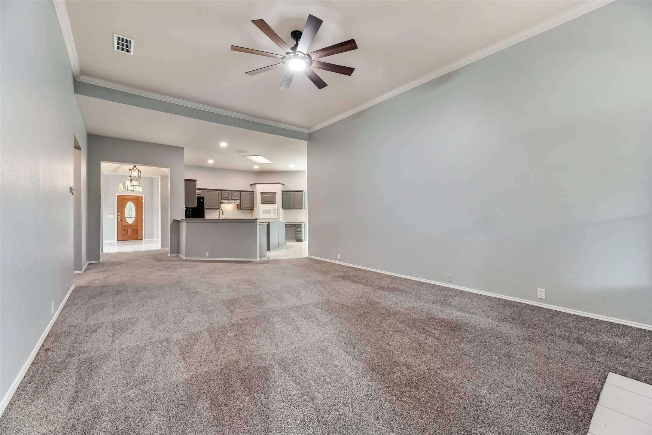 Vaulted ceiling, ceiling fan, gray carpet, gray walls, and recessed lighting