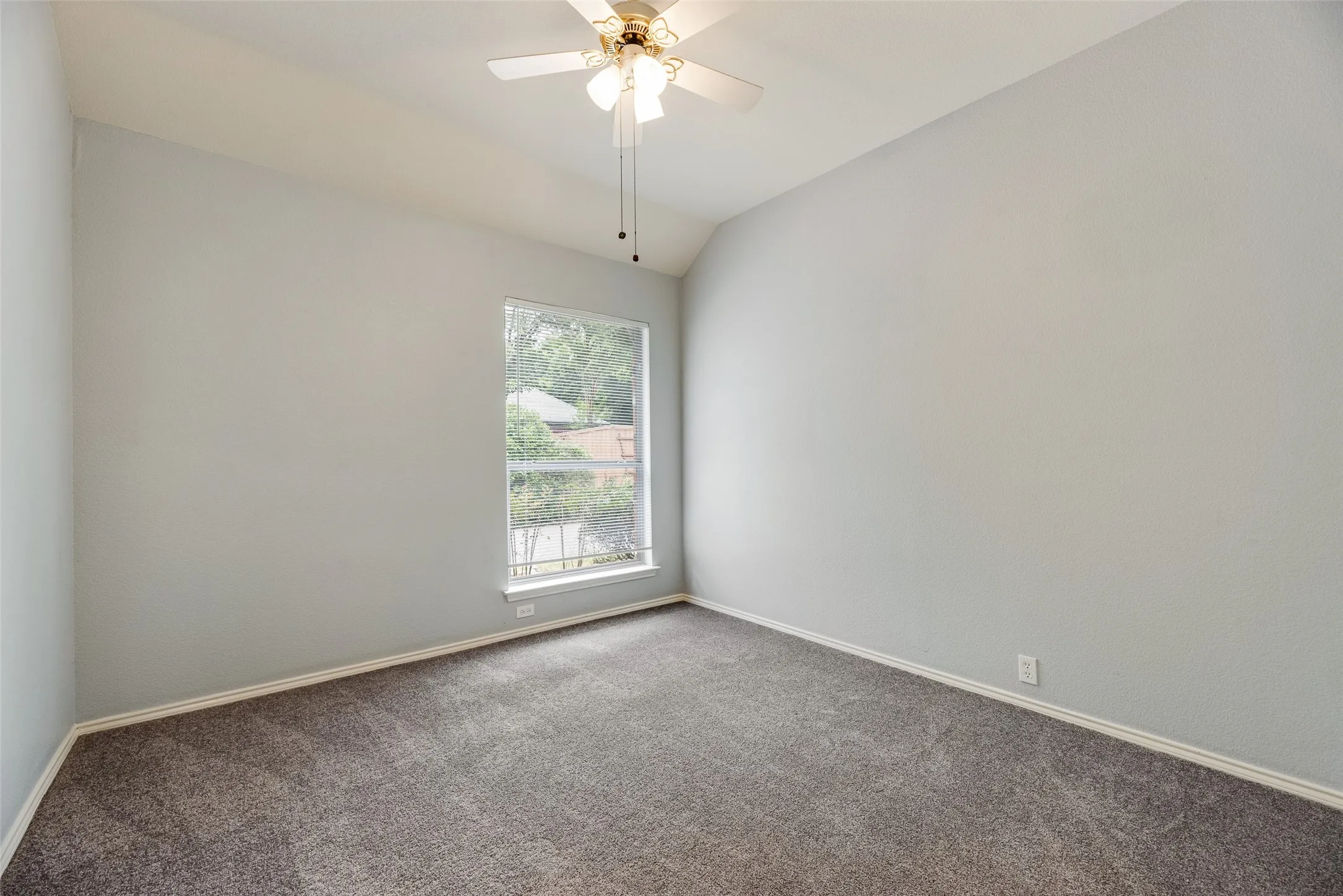 Vaulted ceiling, ceiling fan, window, wall-to-wall carpeting, light-toned walls