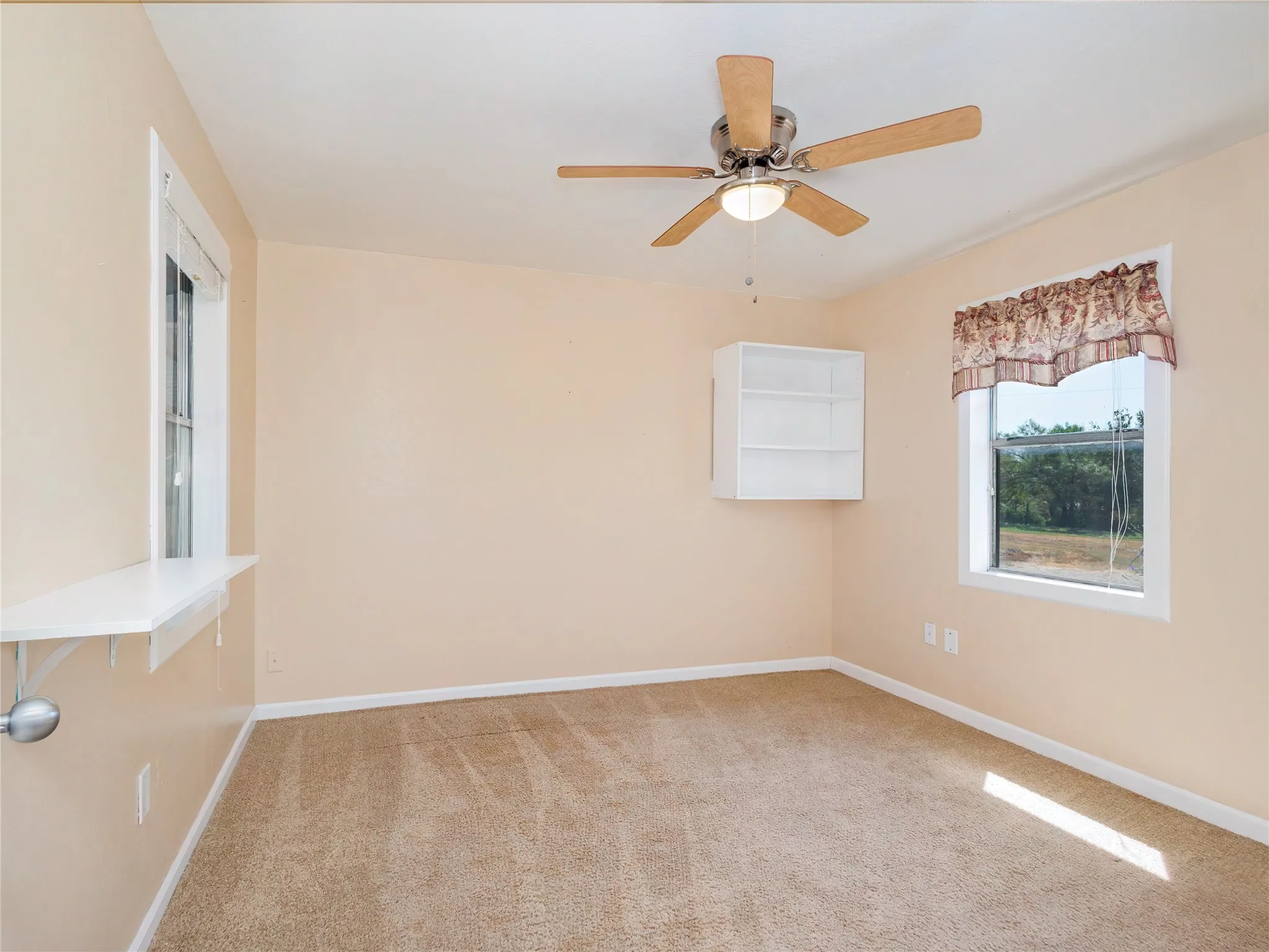 Neutral-toned carpeting, ceiling fan with integrated lighting, and multiple windows