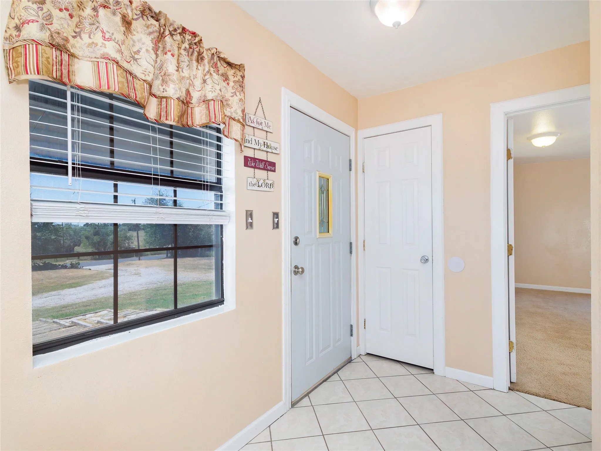 Tile flooring entryway with a paneled door featuring a decorative glass insert