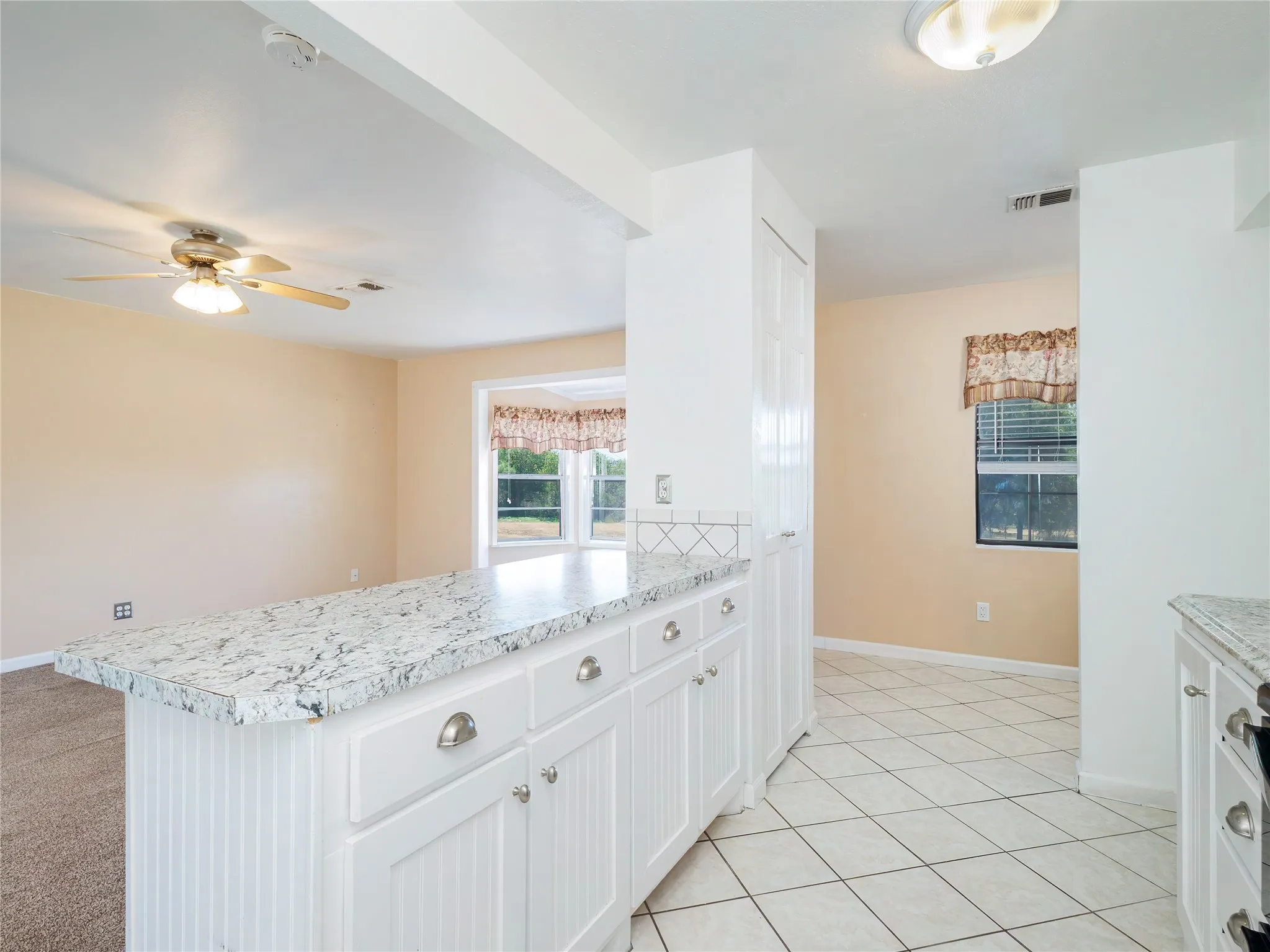 Kitchen with granite-look countertops, white cabinetry with brushed nickel hardware, and tile flooring