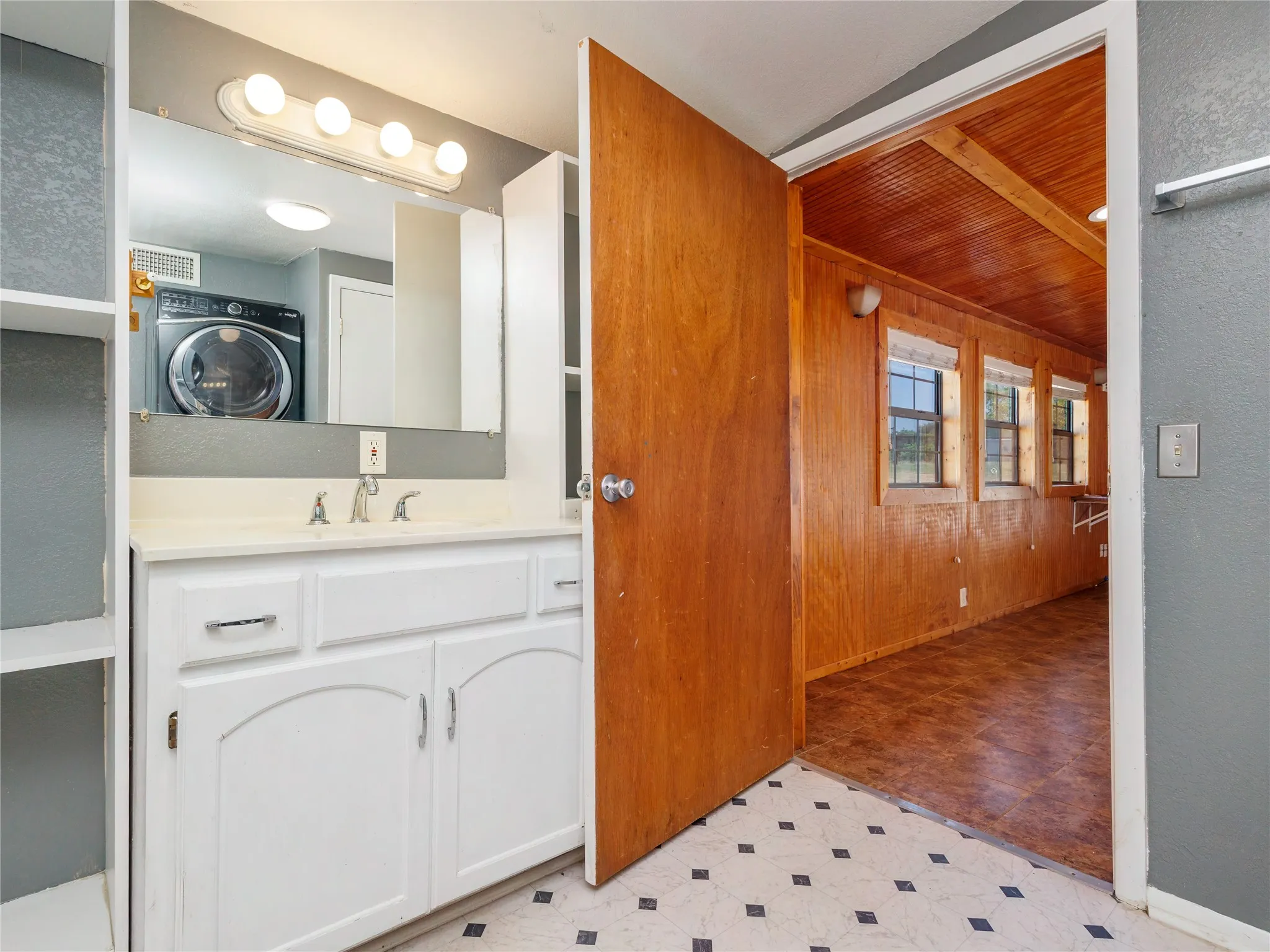 White vanity with dual-handle faucet, integrated sink, and overhead light bar
Second Bathroom and Laundry Room