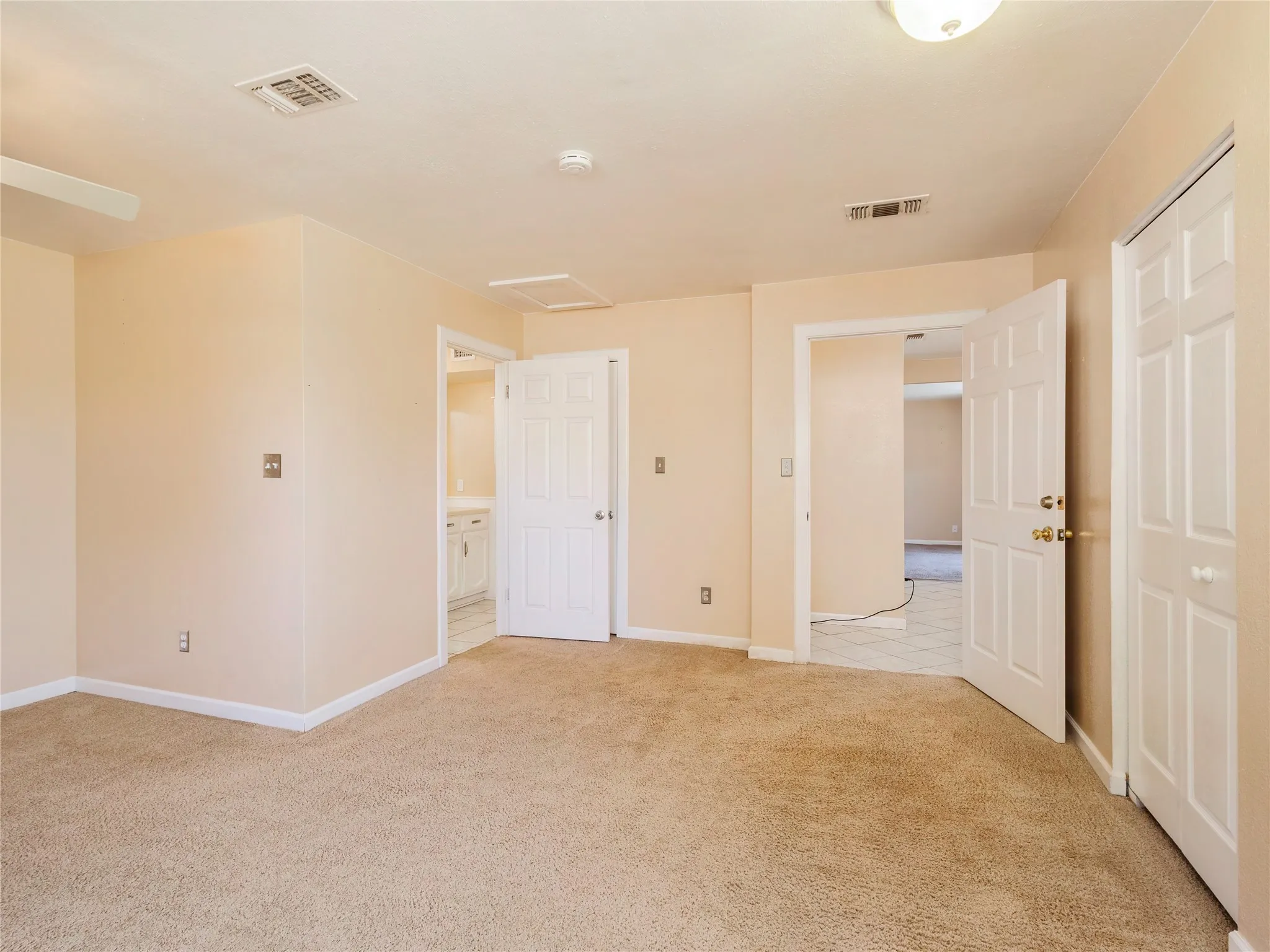 Carpeted flooring, ceiling-mounted light fixture, and multiple panel doors