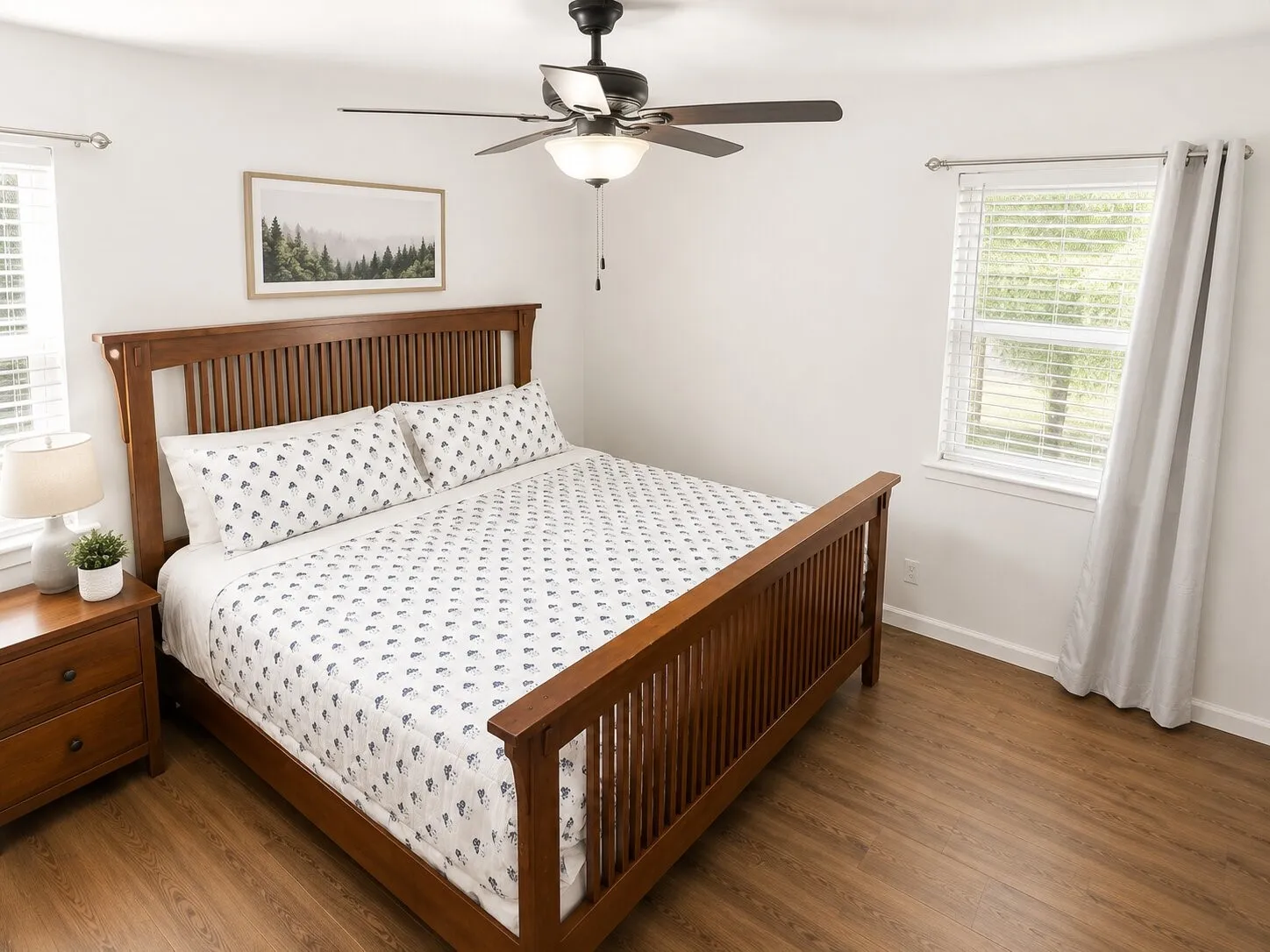 Wood-finish flooring with white walls and a ceiling fan