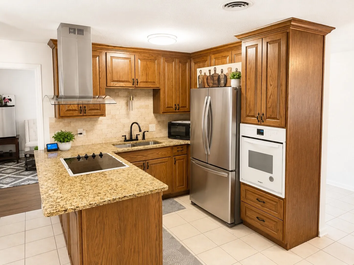 Kitchen featuring wood cabinetry, built-in oven, stainless steel refrigerator, and cooktop on granite countertops with a tile backsplash