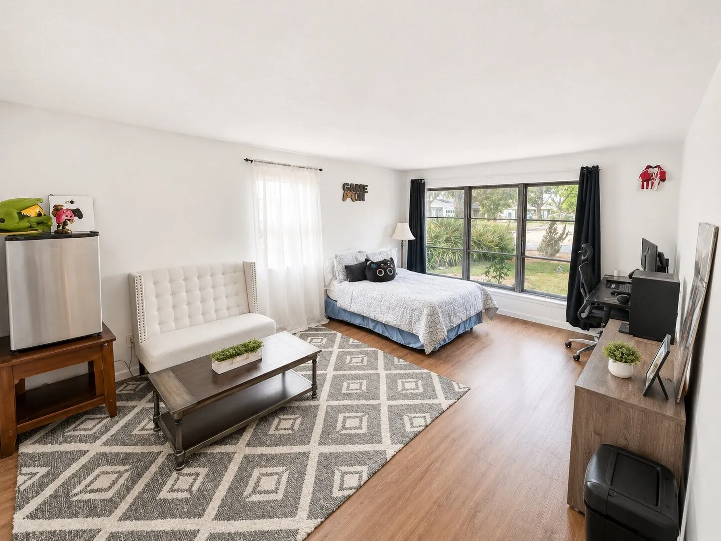 Light wood-finish flooring, white walls, and large windows with black trim