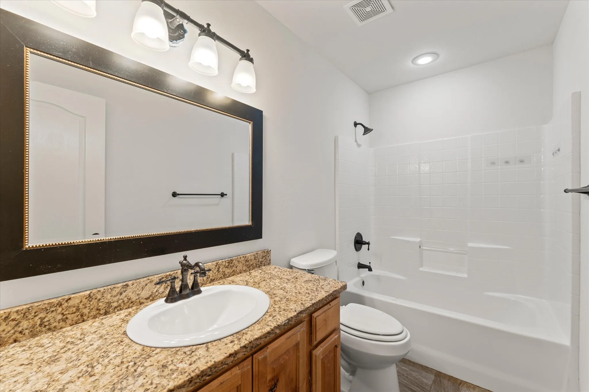 Vanity with a granite-style countertop, undermount sink, and bronze-finish faucet
