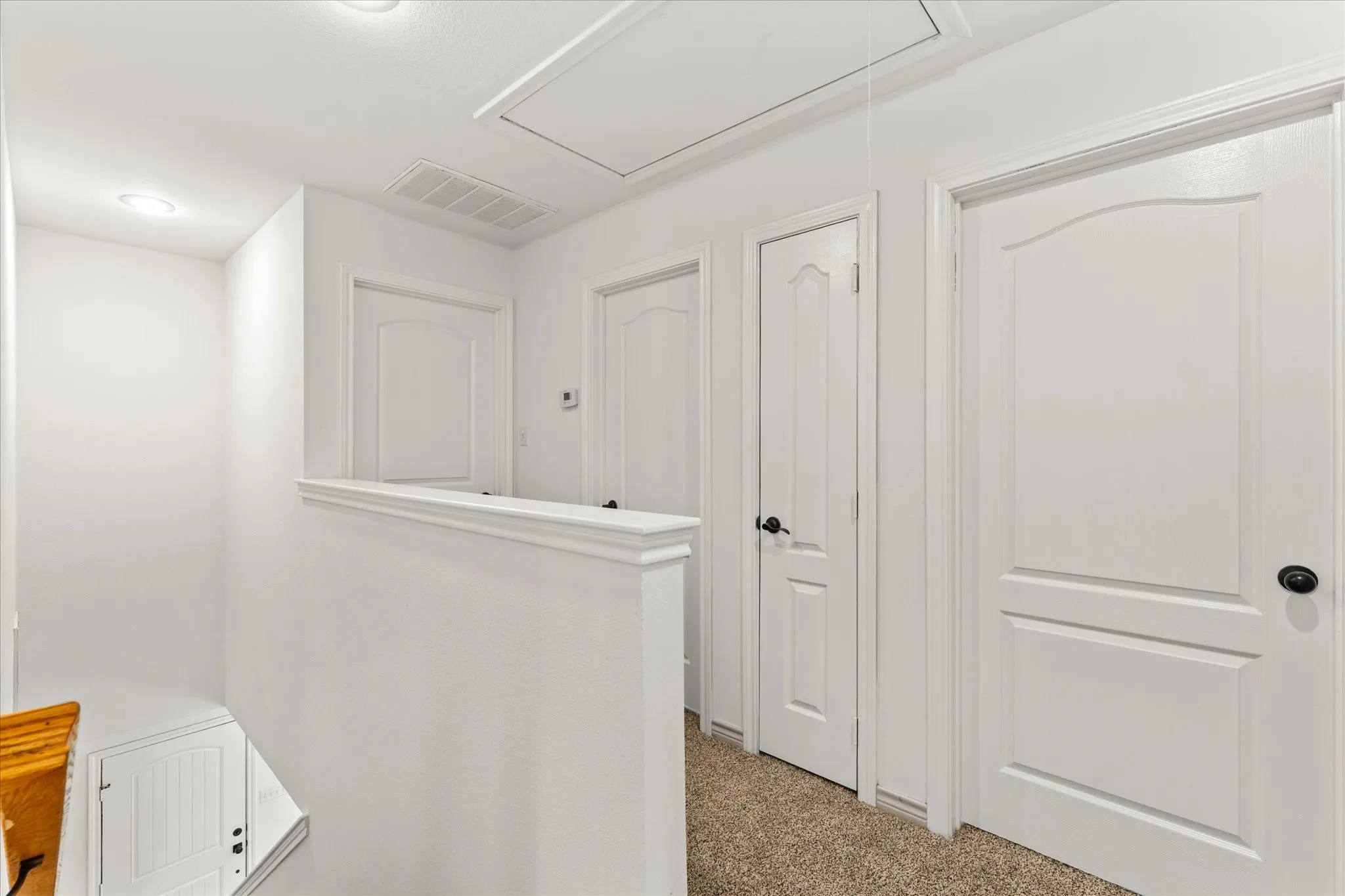 Recessed lighting, white walls, carpeted flooring, paneled doors, black door hardware
