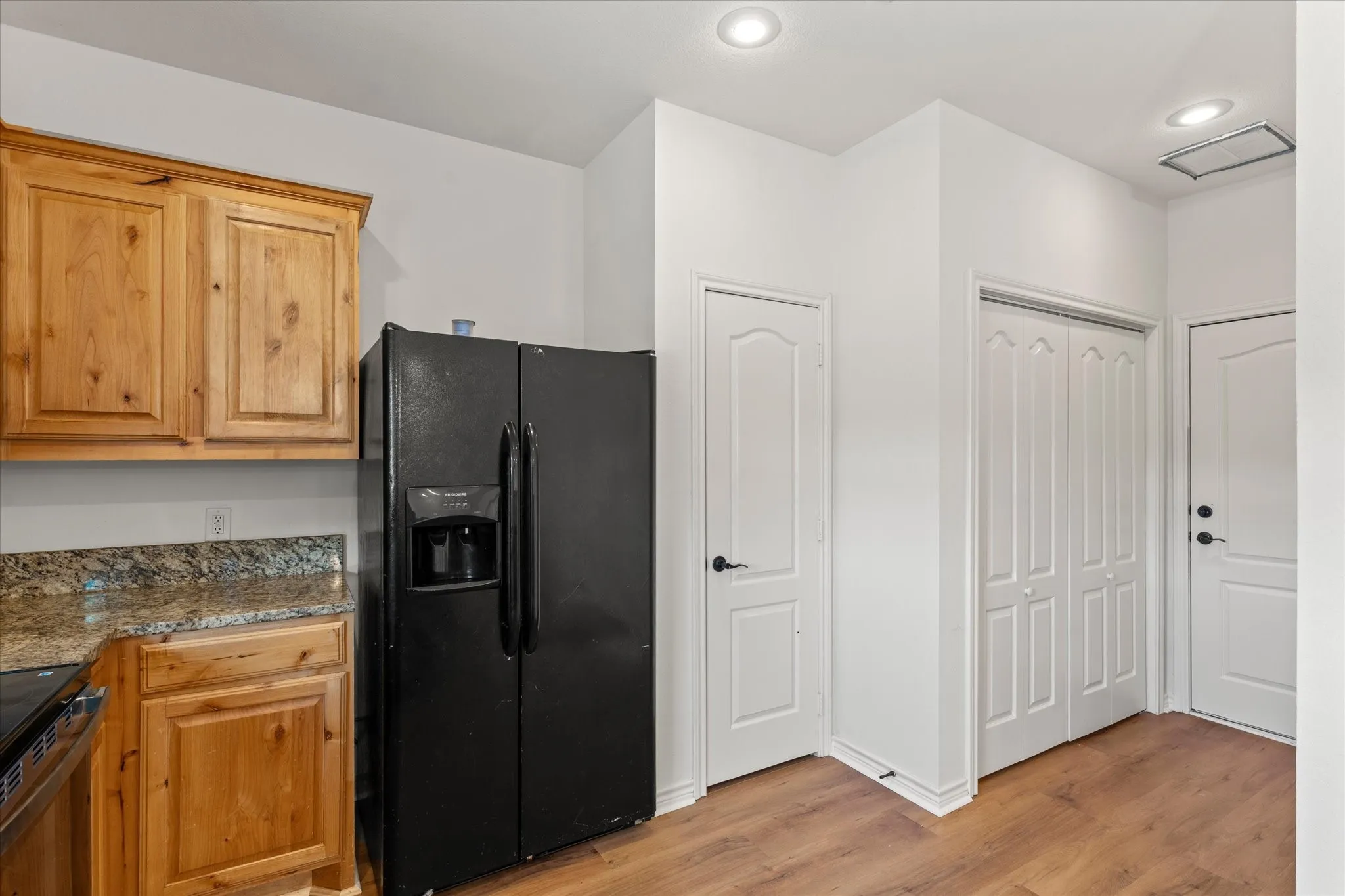 Kitchen featuring wood cabinetry, stone countertops, and wood-finish flooring