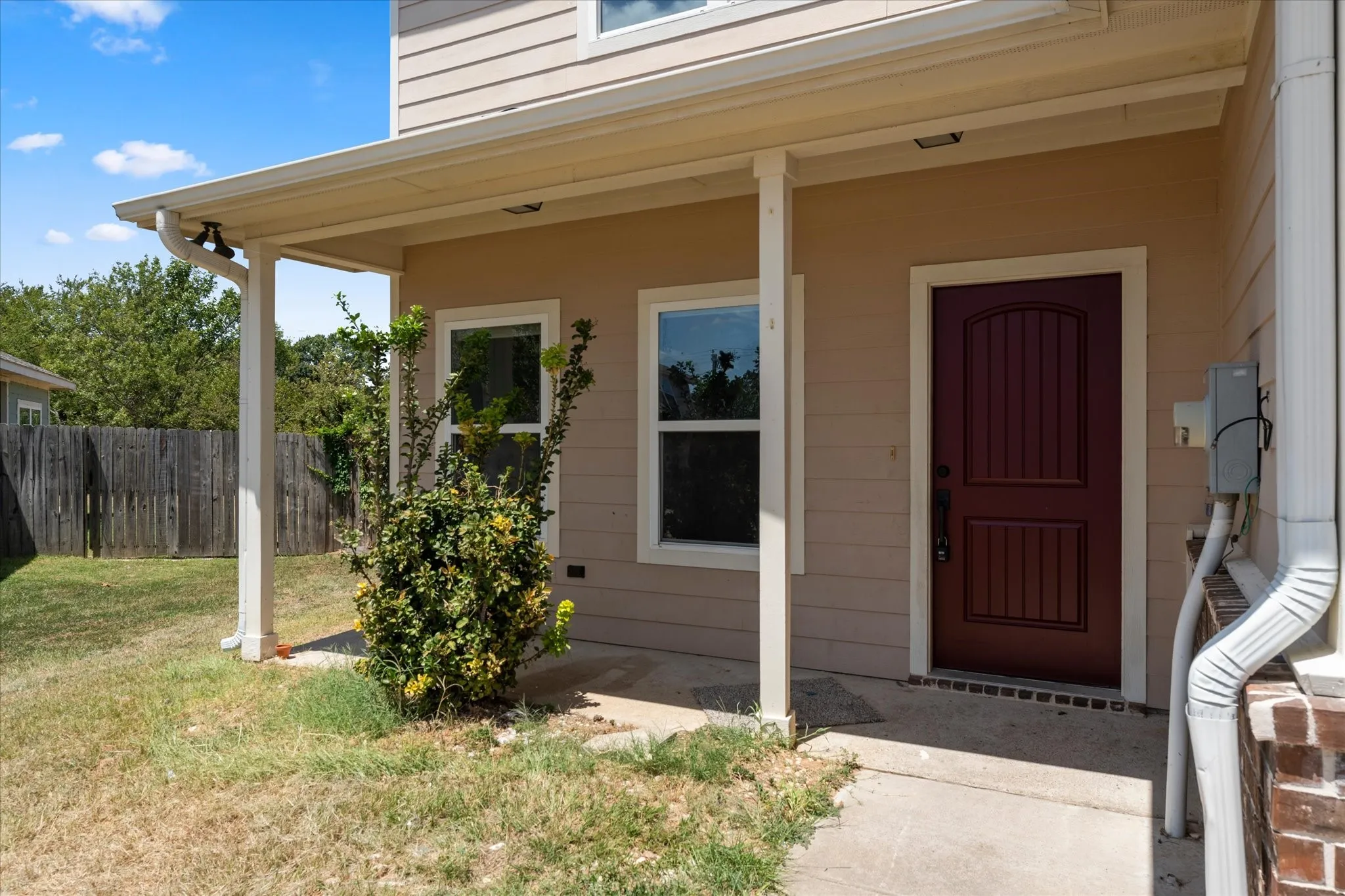 Covered porch entry with a paneled door, multiple windows, and exterior siding