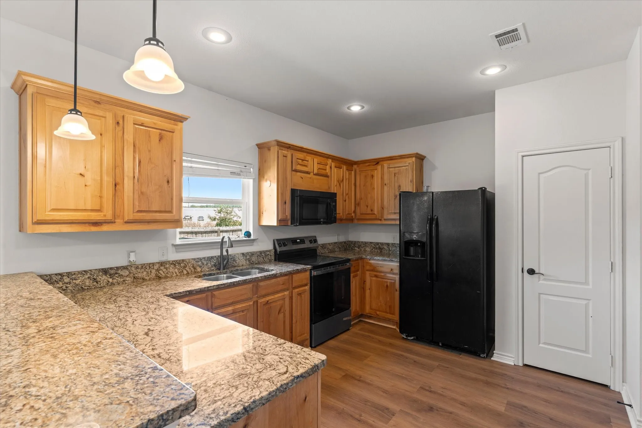 Kitchen featuring wood-finish flooring, wood cabinetry, stone countertops, and recessed lighting