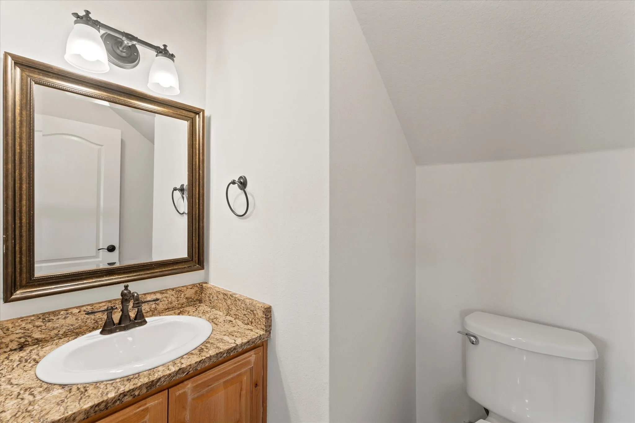 Vanity with granite-style countertop, undermount sink, and wood-finish cabinetry