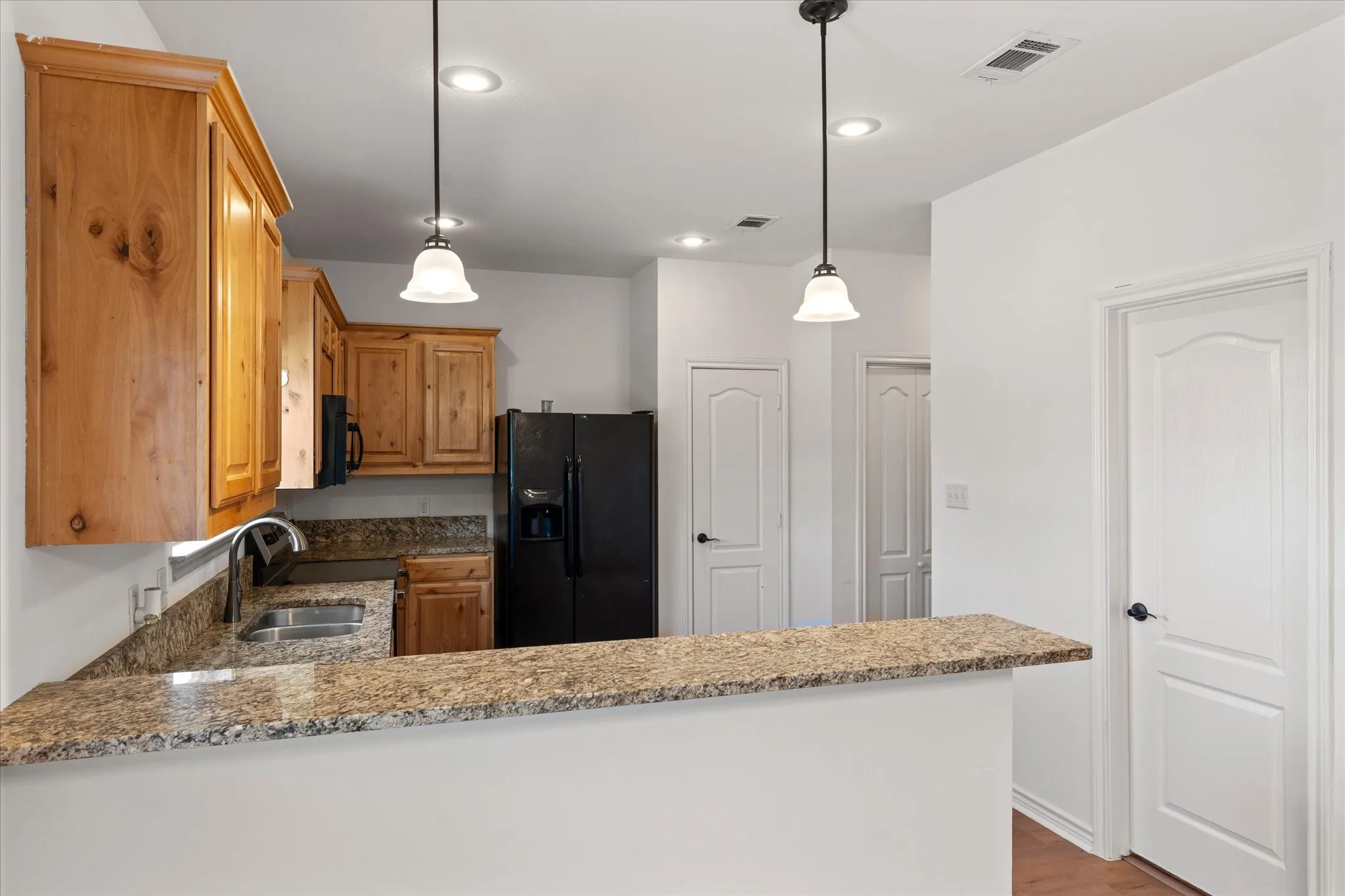Kitchen featuring wood cabinetry, stone countertops, and recessed lighting